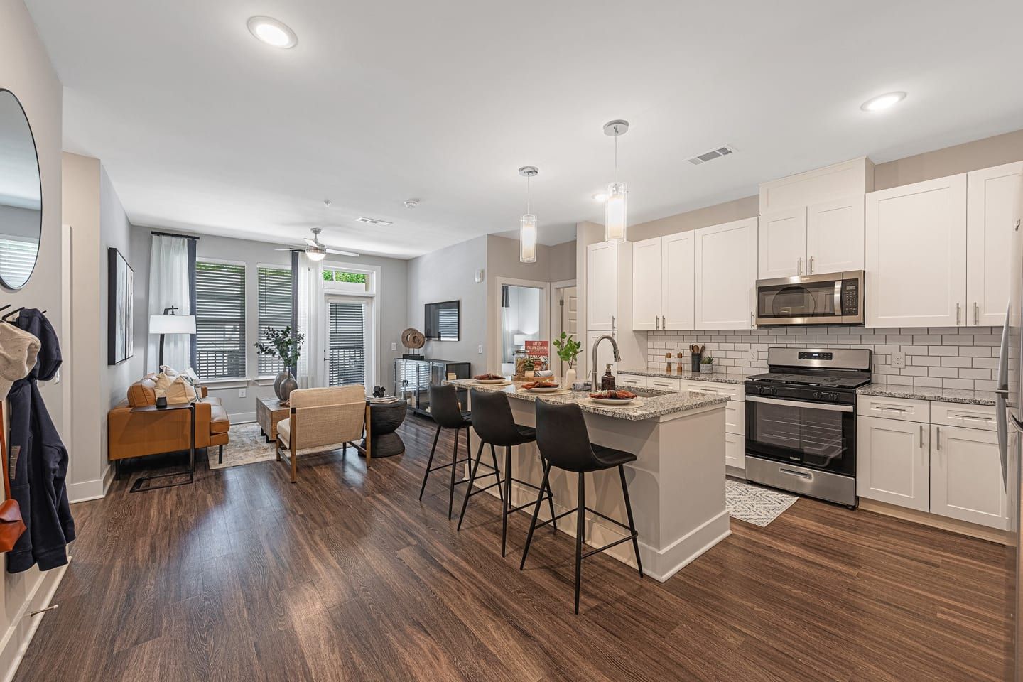 A kitchen and living room in a house with hardwood floors and white cabinets.