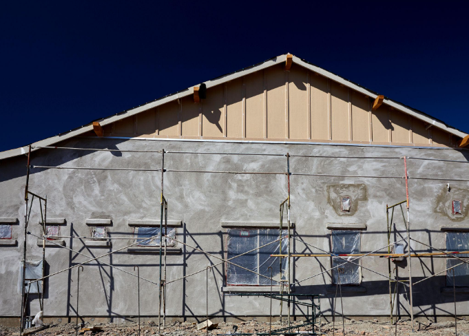 “Building exterior with scaffolding and fresh gray stucco applied across the upper wall during a stucco service in Spring Valley, NV”