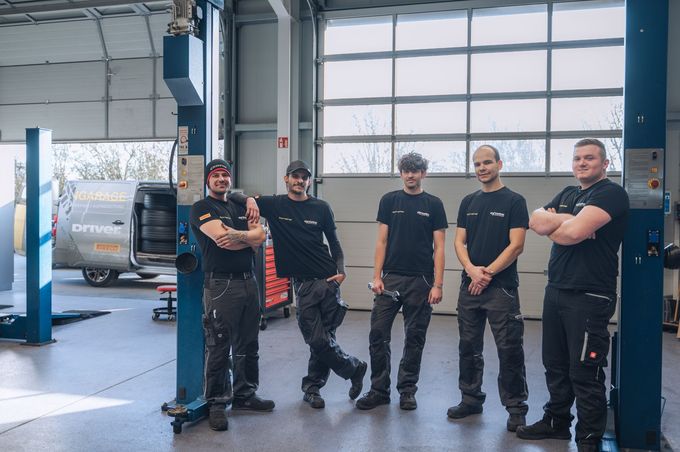 Zwei Männer arbeiten in einer Garage an einer Windschutzscheibe.