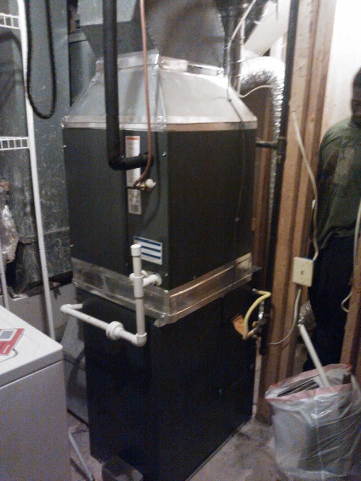 A man is standing next to a heater in a basement