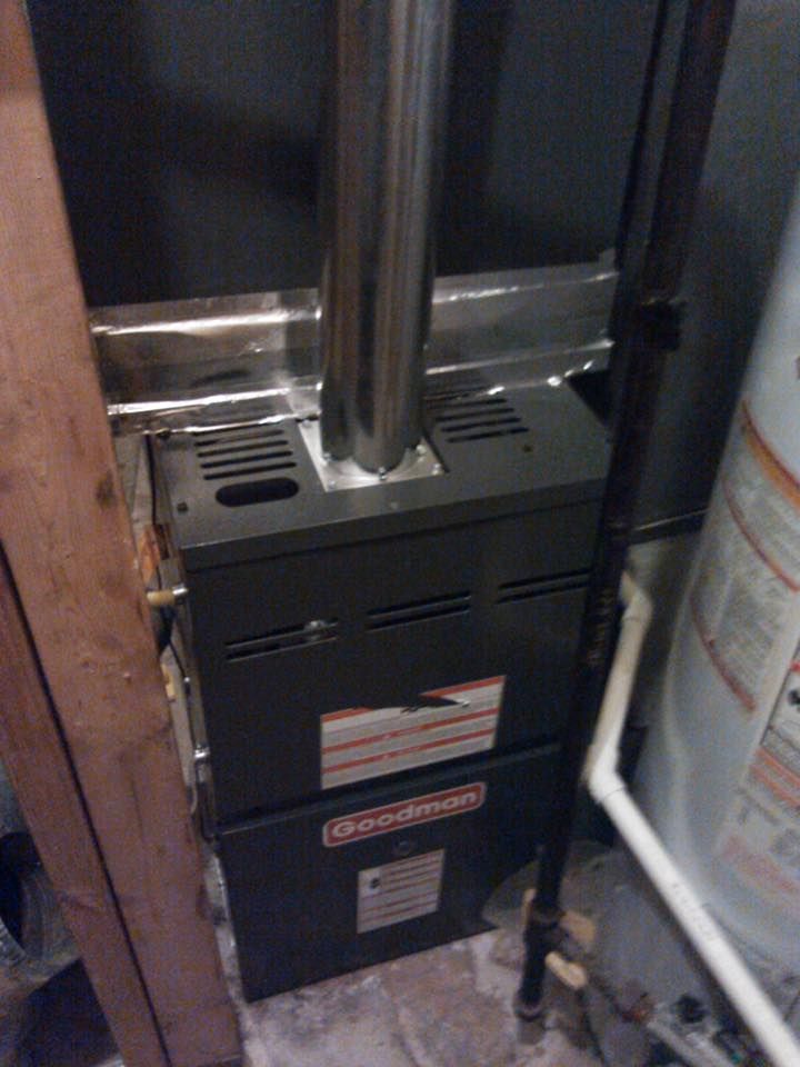 A furnace is sitting next to a water heater in a room.