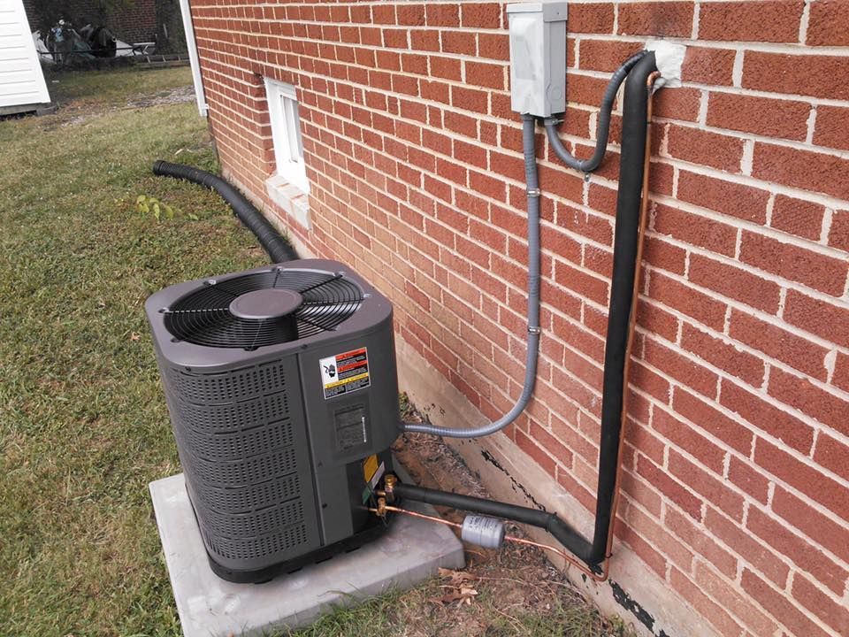 An air conditioner is sitting on the side of a brick building.