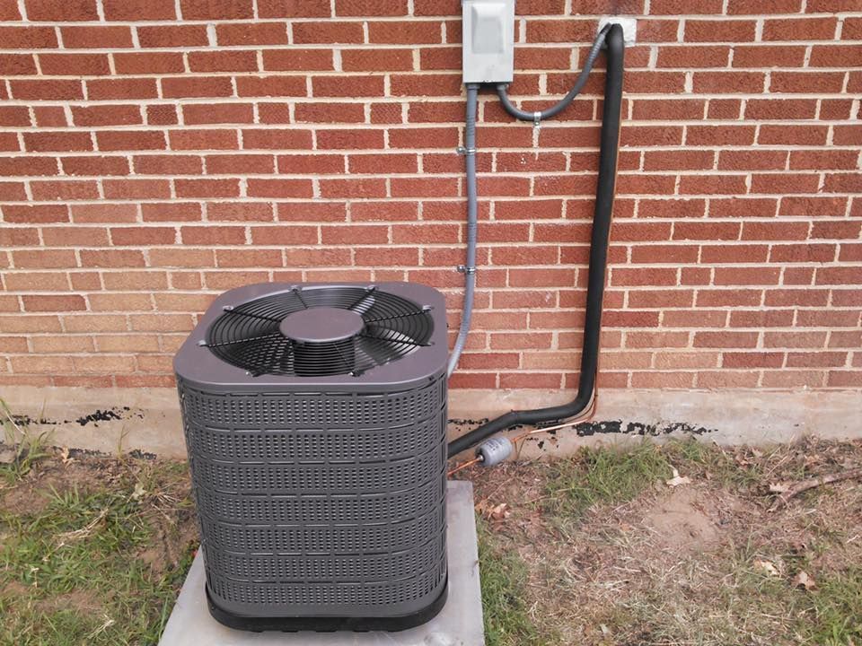 An air conditioner is attached to a brick wall.