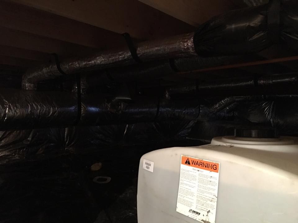 A water heater is sitting under a ceiling in a basement.