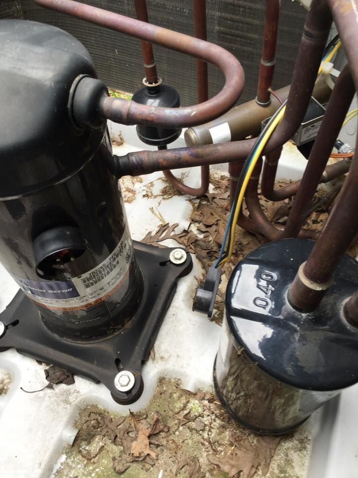 A close up of a compressor and pipes on a white surface.