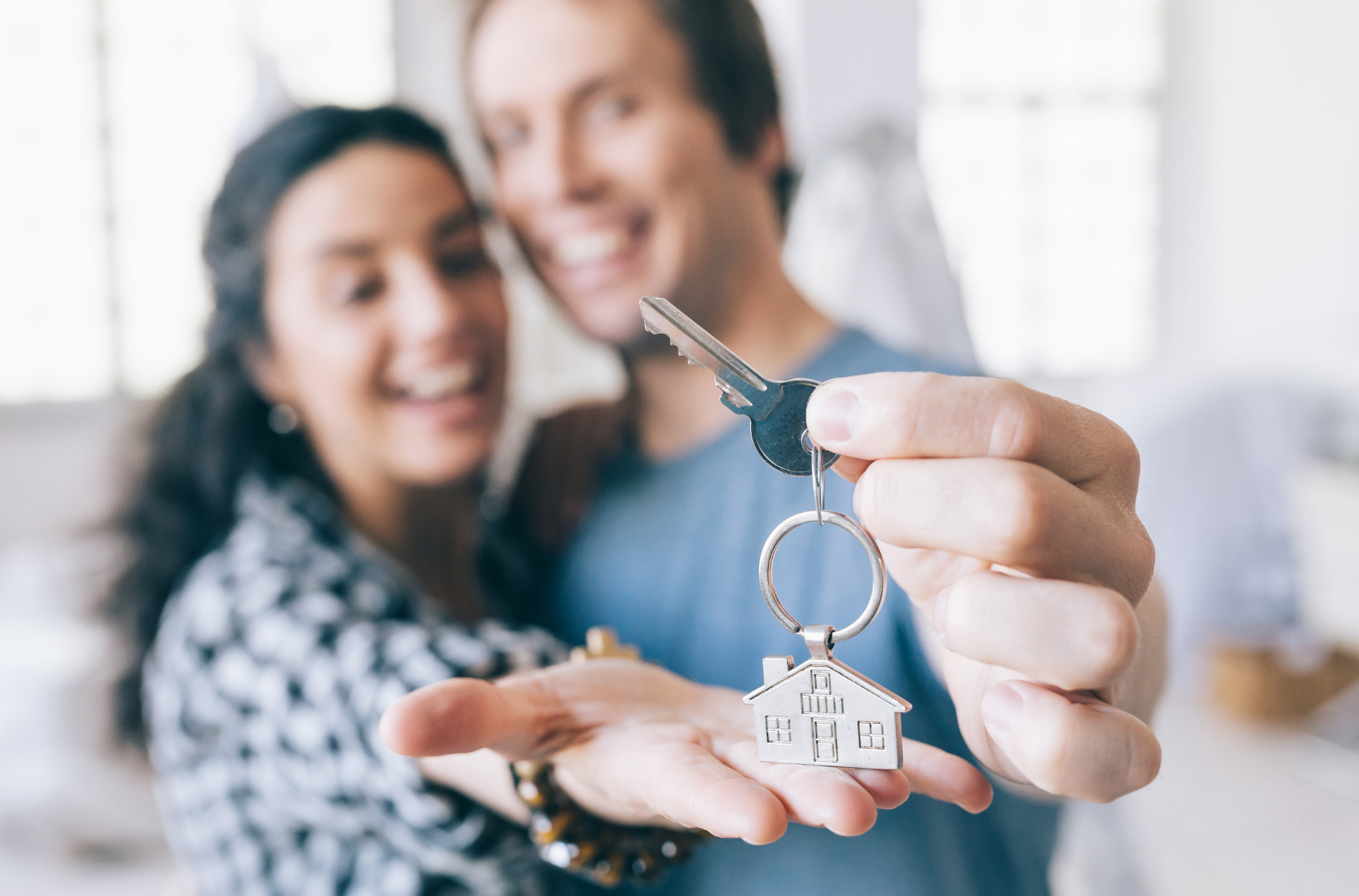 A man and a woman are holding keys to their new home.