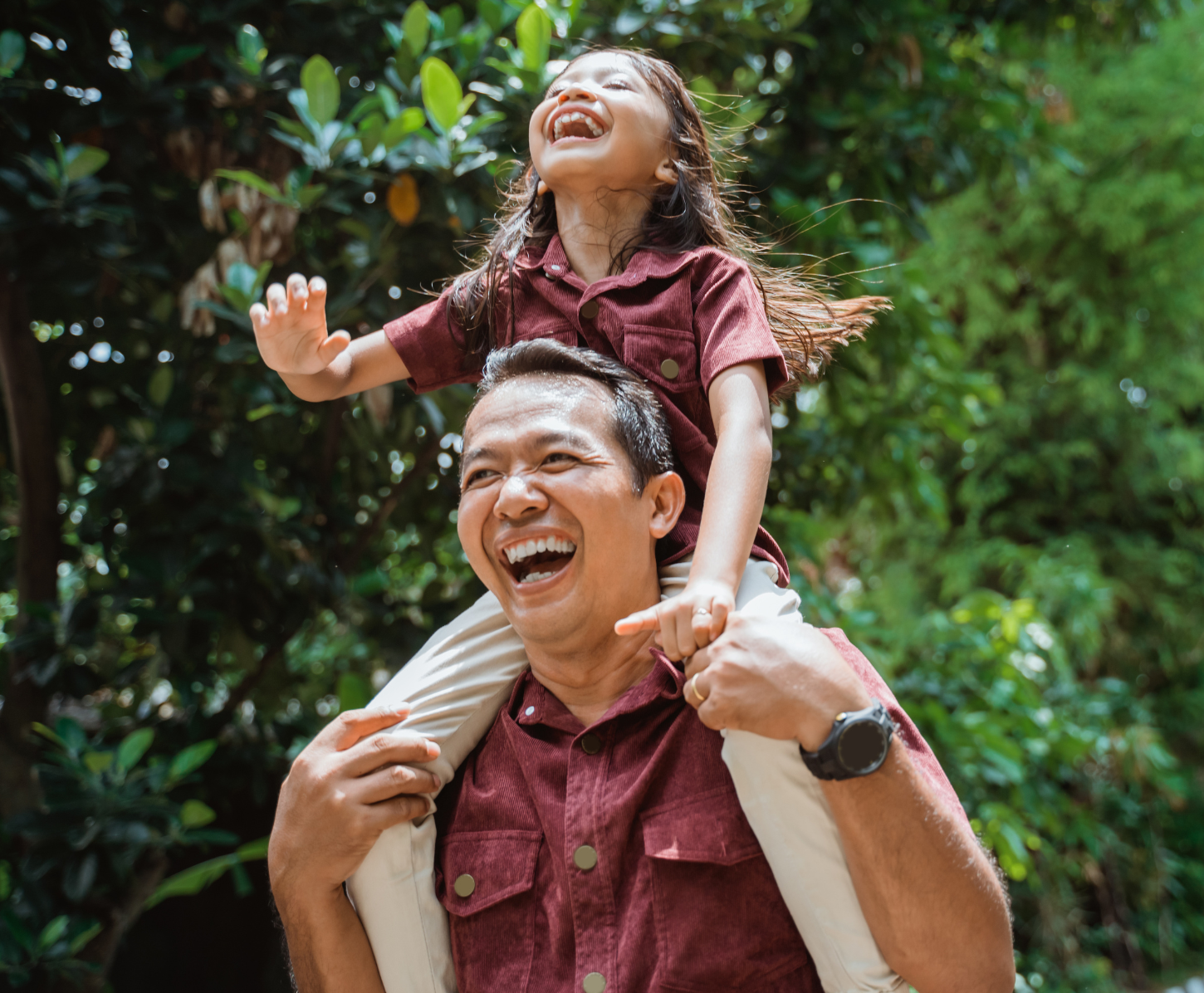 A man is carrying a little girl on his shoulders.