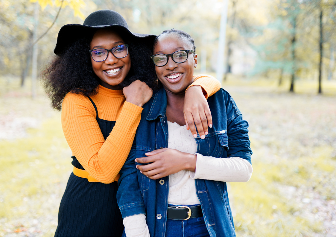 Two young women are hugging each other in a park.
