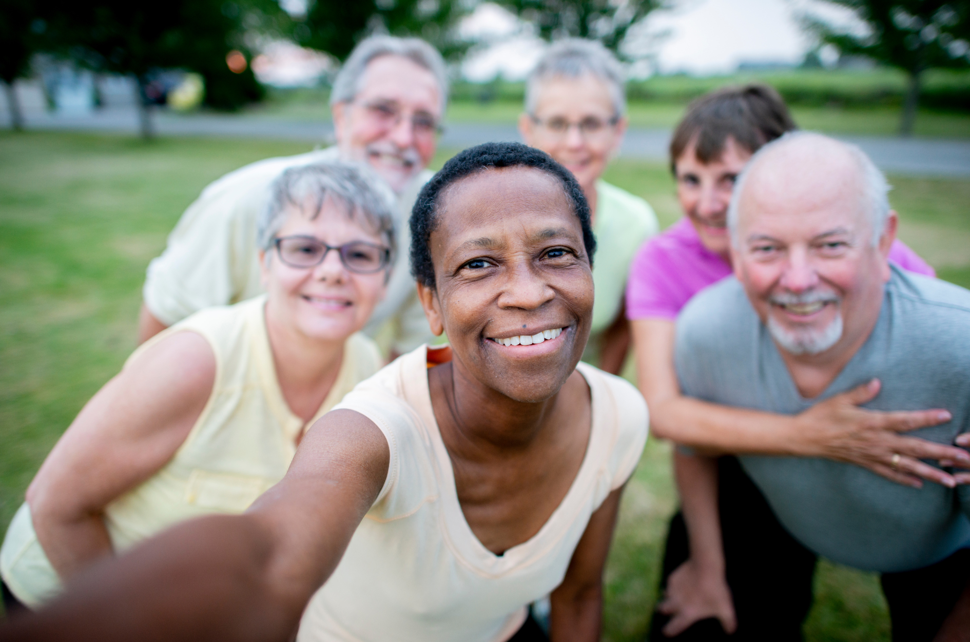 A group of older people are taking a selfie in a park.