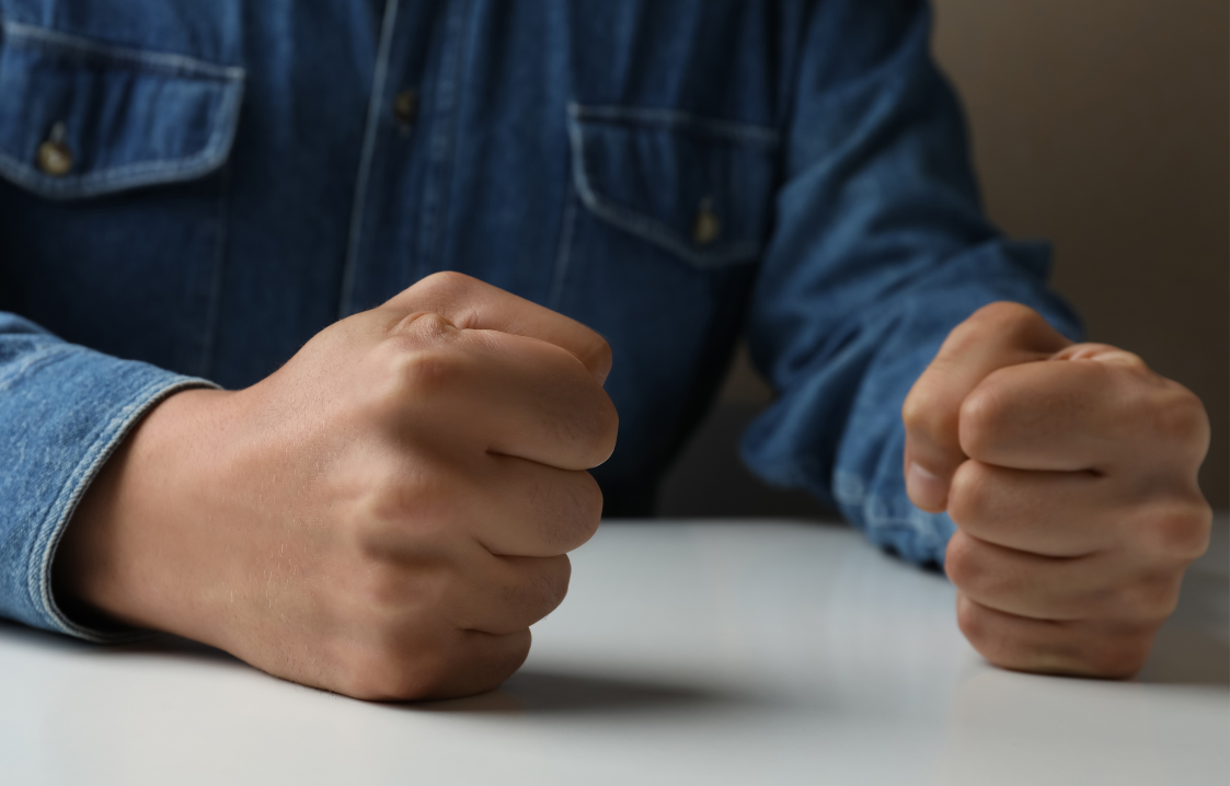 A man is sitting at a table with his fist in the air.