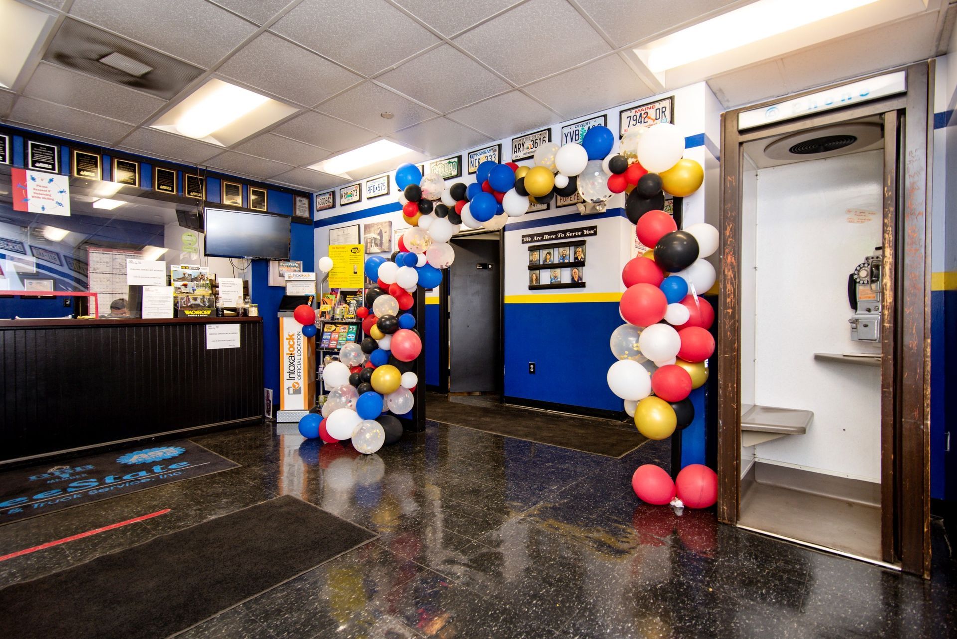 Lobby of an auto repair shop decorated with balloons, front desk, blue and black flooring, open doorway | Freestate Auto & Truck Service