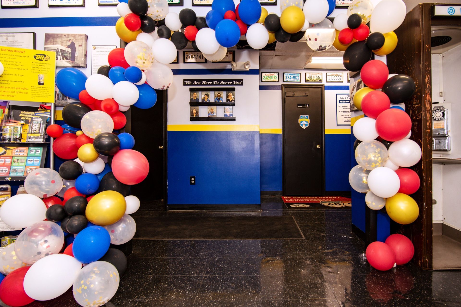 Entrance decorated with red, white, blue, yellow, and black balloons. Blue walls with framed items in the background | Freestate Auto & Truck Service