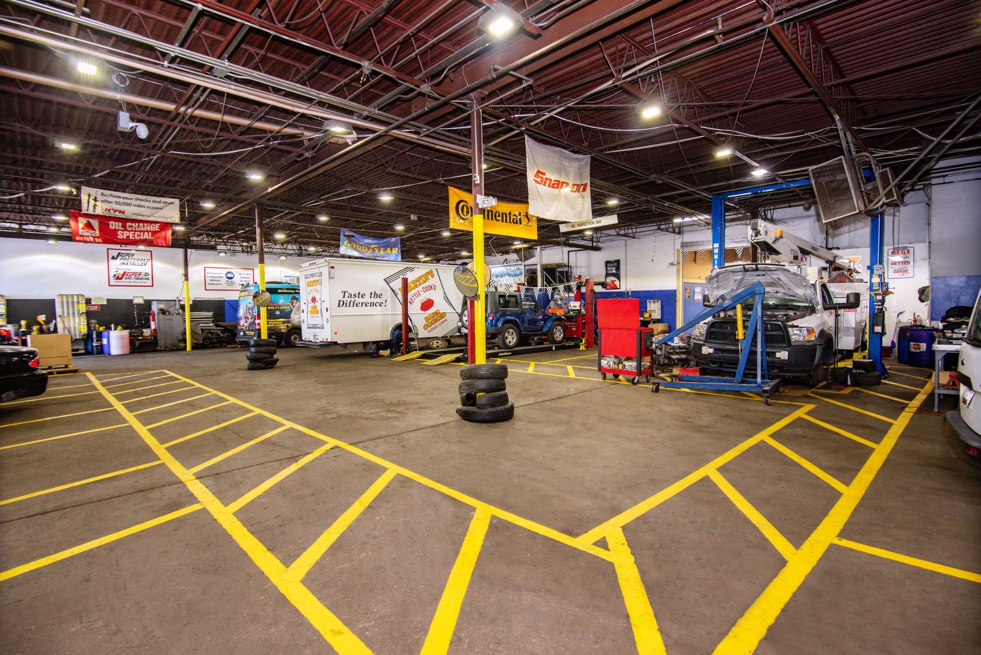 Interior of a car repair shop with several vehicles, tools, and yellow lane markings | Freestate Auto & Truck Service