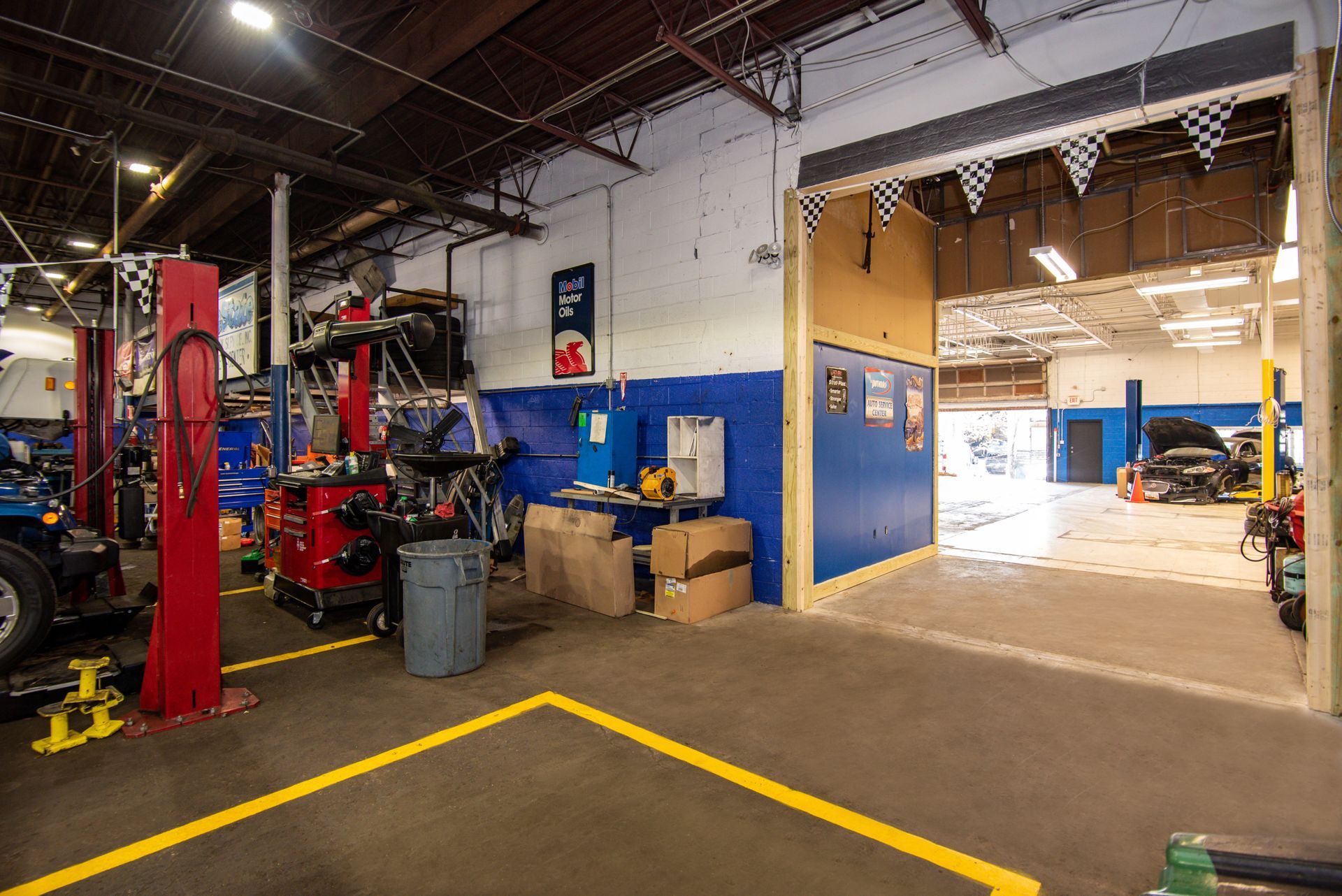 Interior of a car repair shop with several bays and tools. Yellow floor lines and open garage door | Freestate Auto & Truck Service
