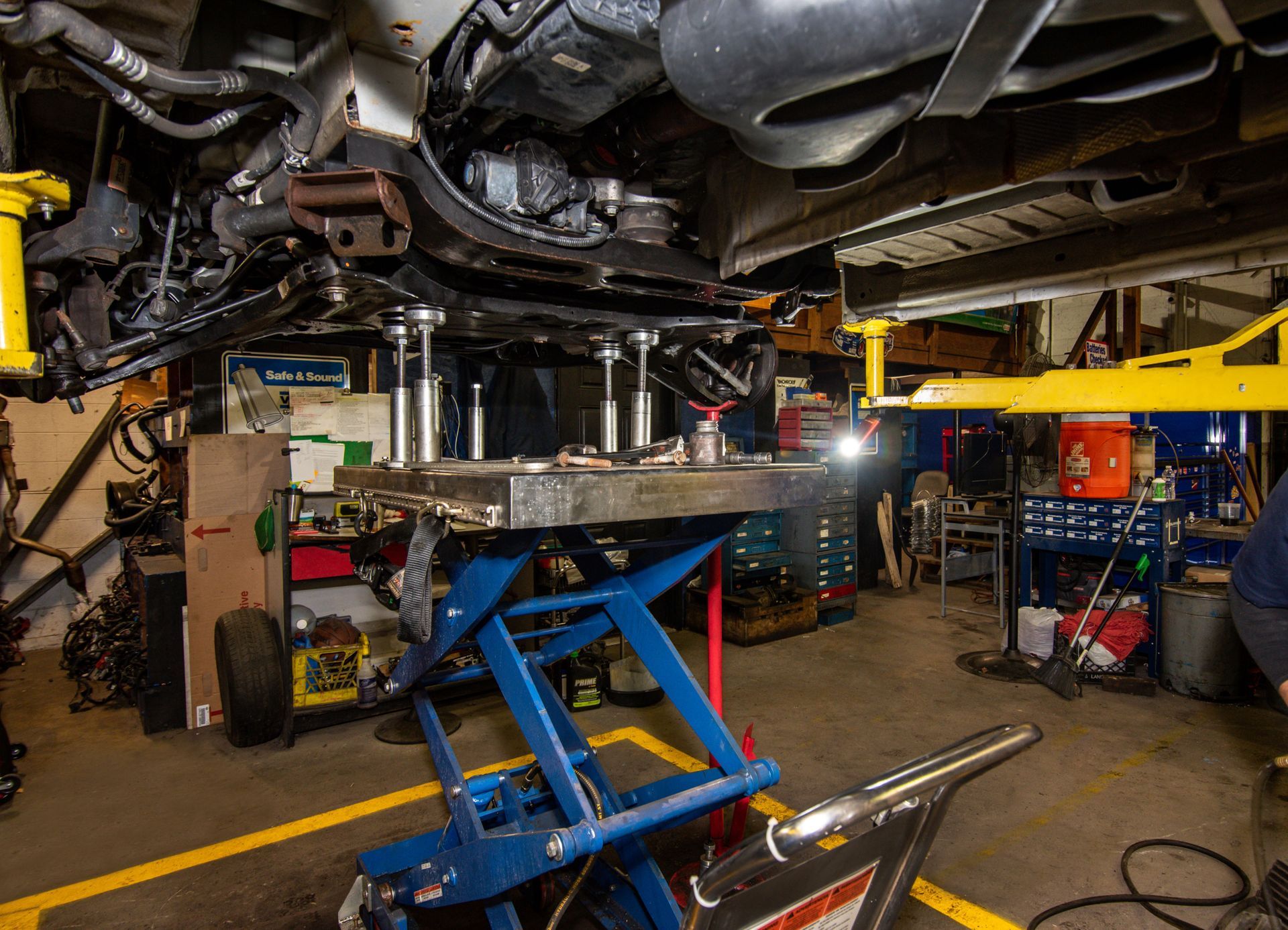 Car being repaired in a repair shop, lifted on jacks, with tools and a blue lift visible | Freestate Auto & Truck Service