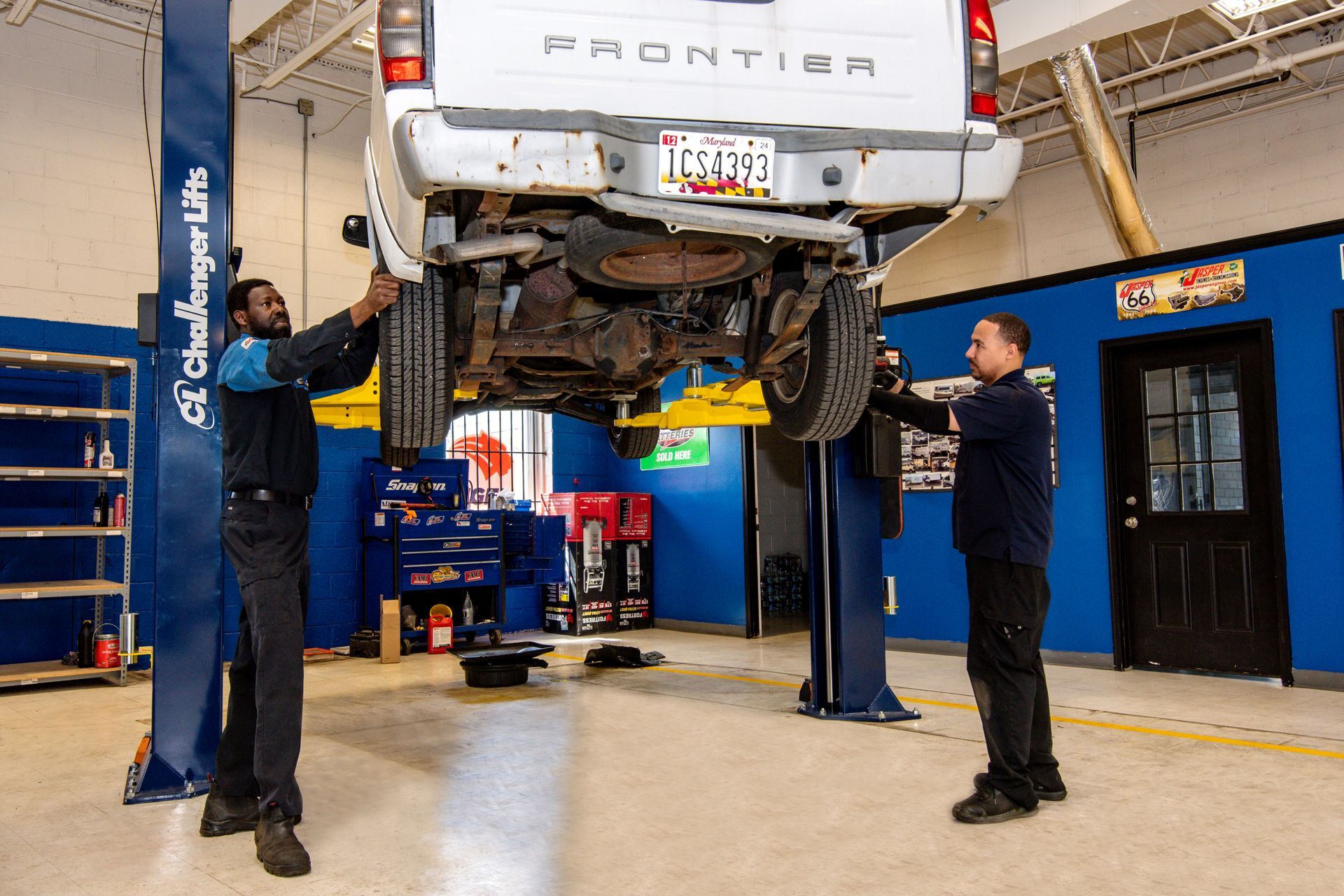 Two mechanics working on a lifted white truck in a garage | Freestate Auto & Truck Service