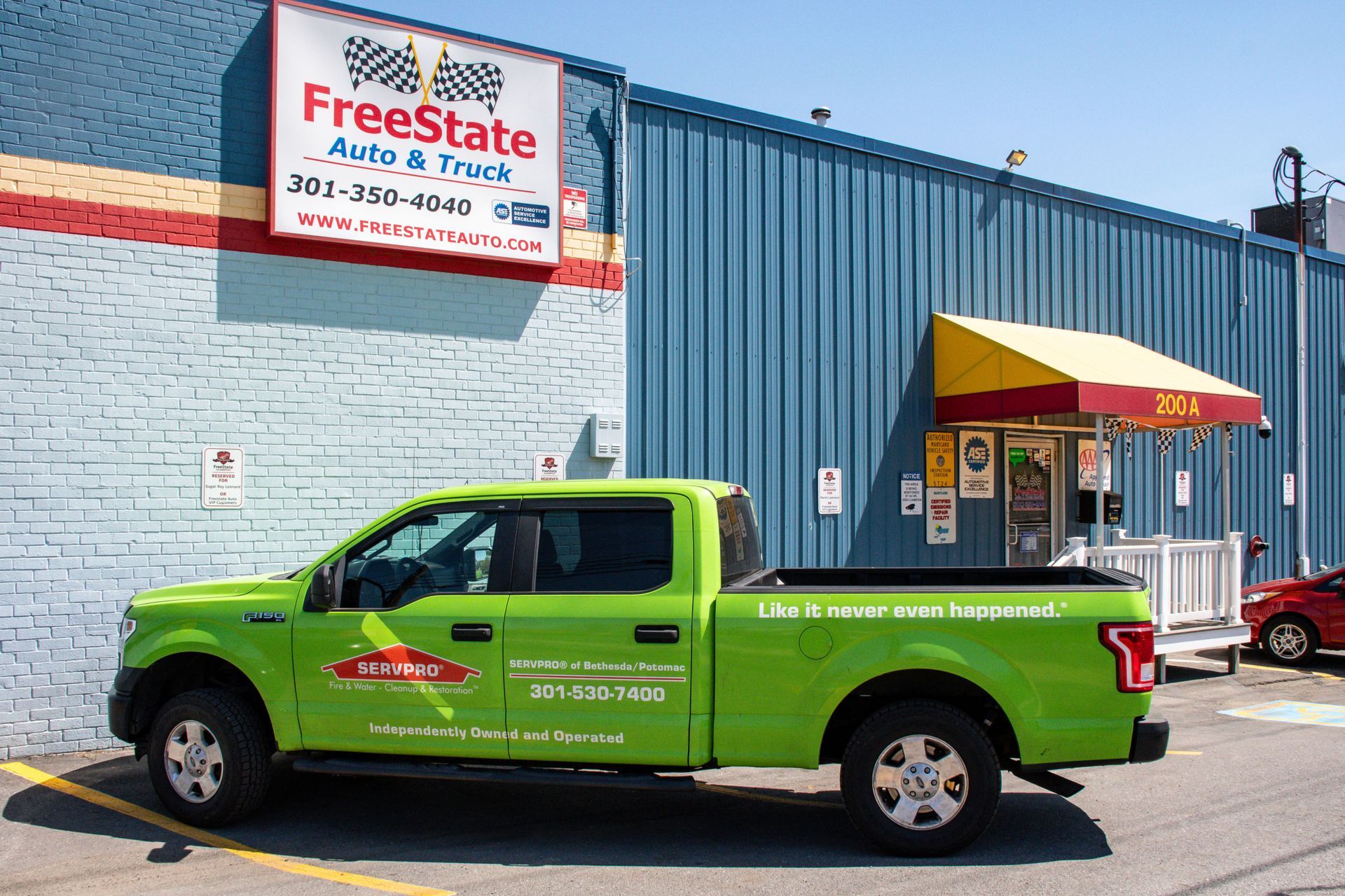 Green FreeState Auto & Truck pickup truck parked outside the auto shop building with blue siding | Freestate Auto & Truck Service