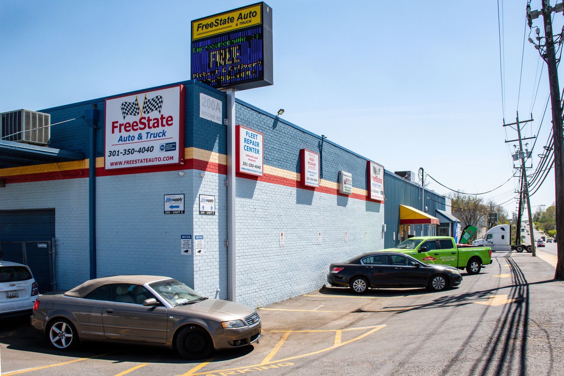 FreeState Auto building with parked cars, blue, yellow and red accents. Sign: Arnold Tire Auto | Freestate Auto & Truck Service