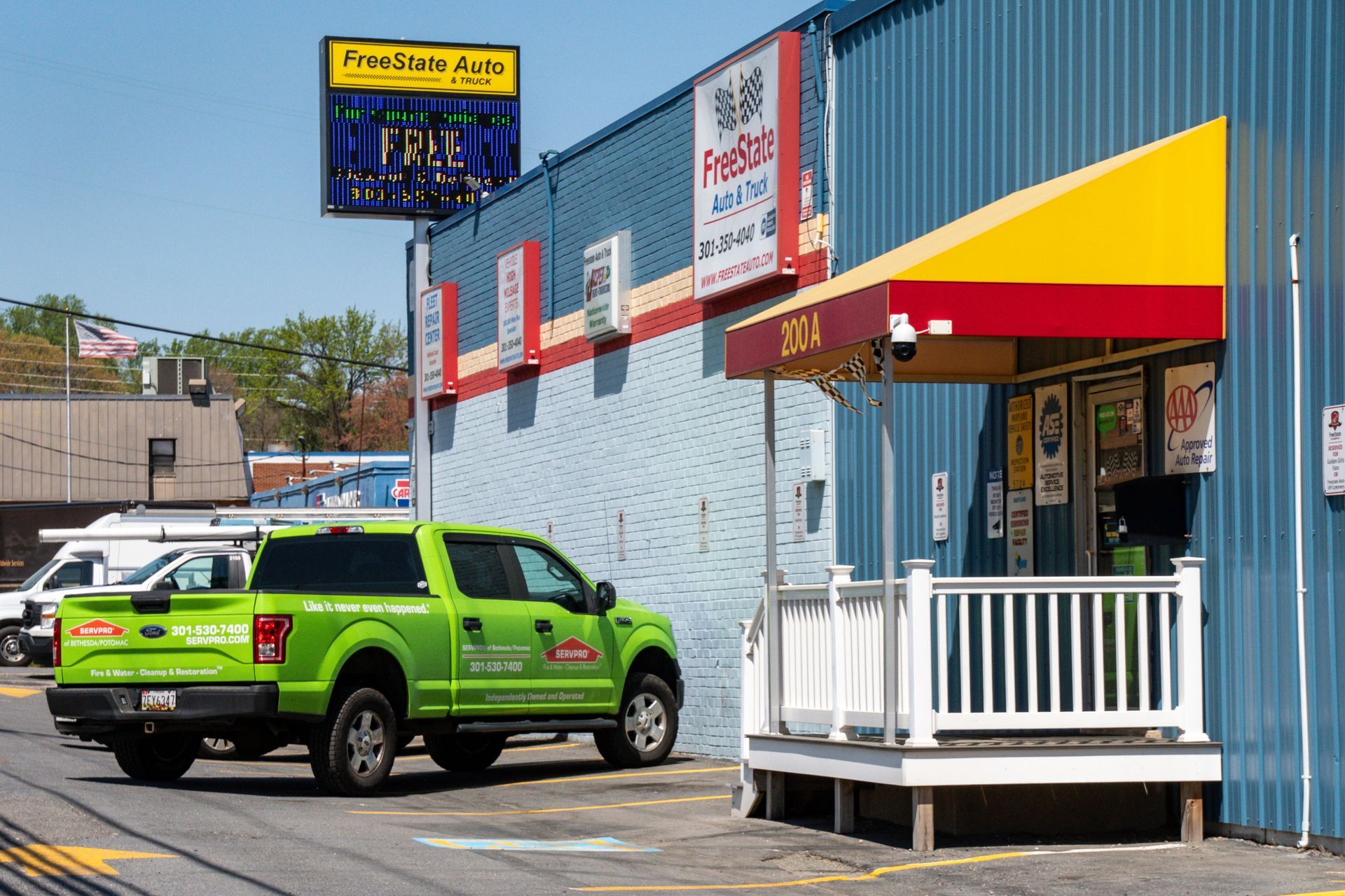Green truck parked outside a business with a yellow and red awning | Freestate Auto & Truck Service