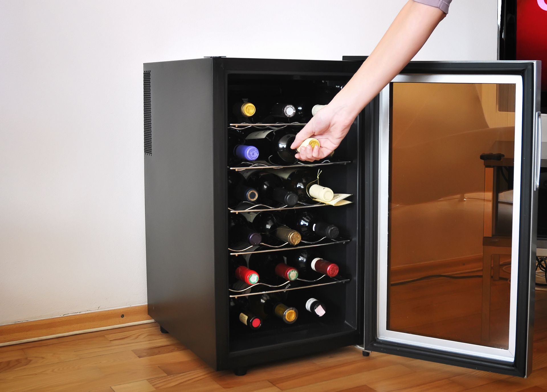 An elegant wine cooler with a transparent glass door, showcasing a collection of chilled wine bottles inside.