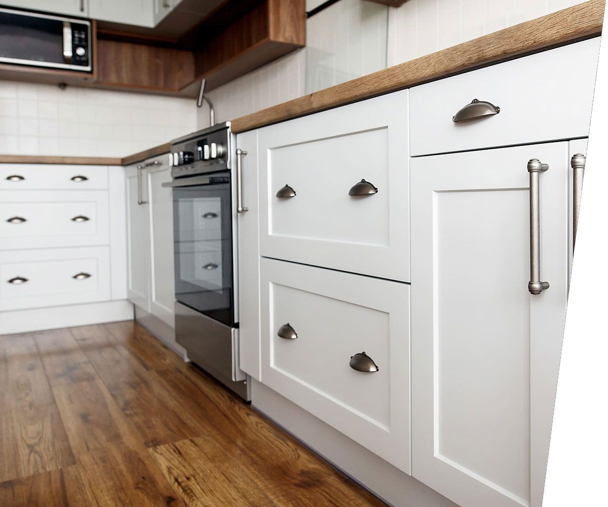 Stylish light gray handles on cabinets close-up, kitchen interior with modern furniture and stainless steel appliances. kitchen design in scandinavian style