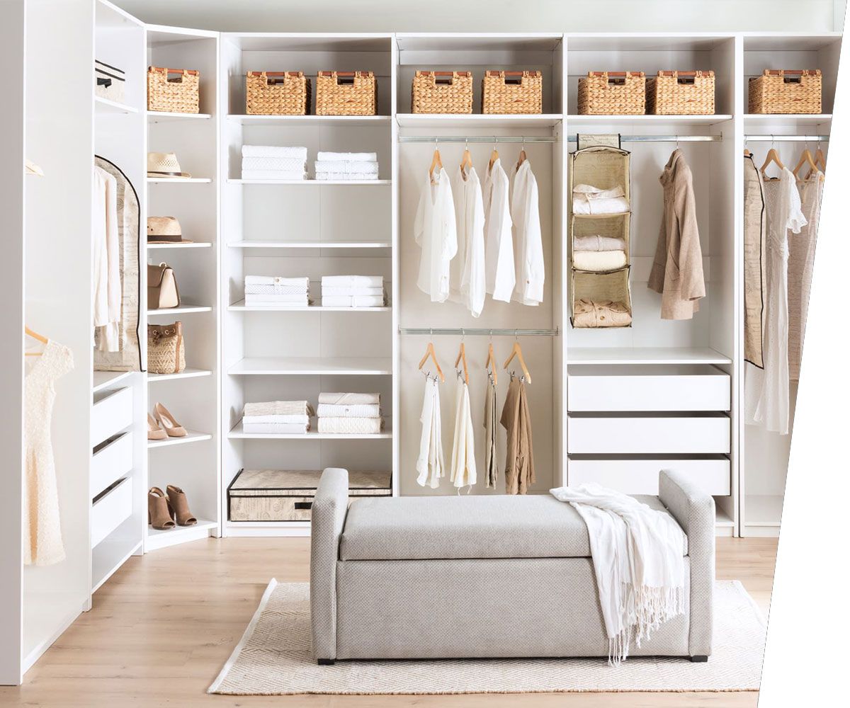 A cozy bedroom with white walls and a closet, featuring clothes hung up in neat fashion