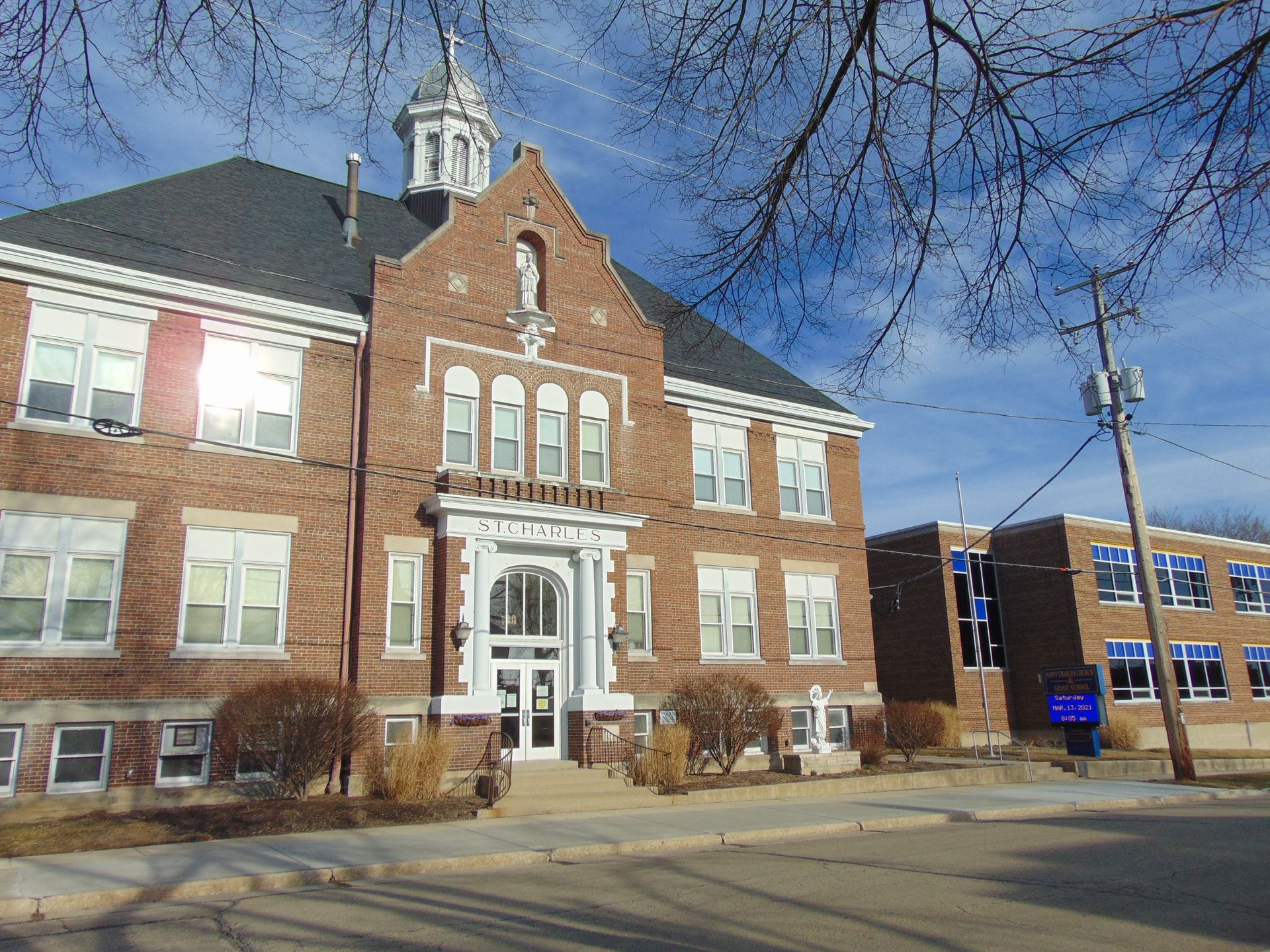 Brick civic building with white trim and central entrance under a clear blue sky