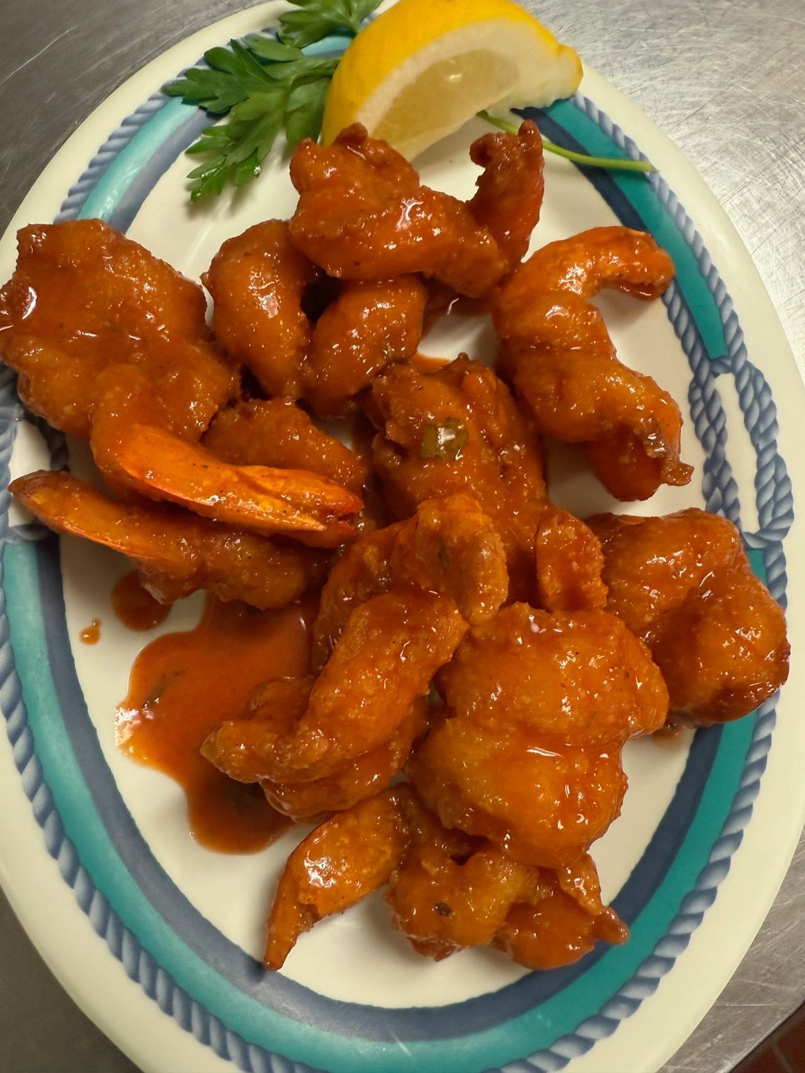 Plate of fried shrimp in red sauce, garnished with lemon and parsley. At High Tide Harry's