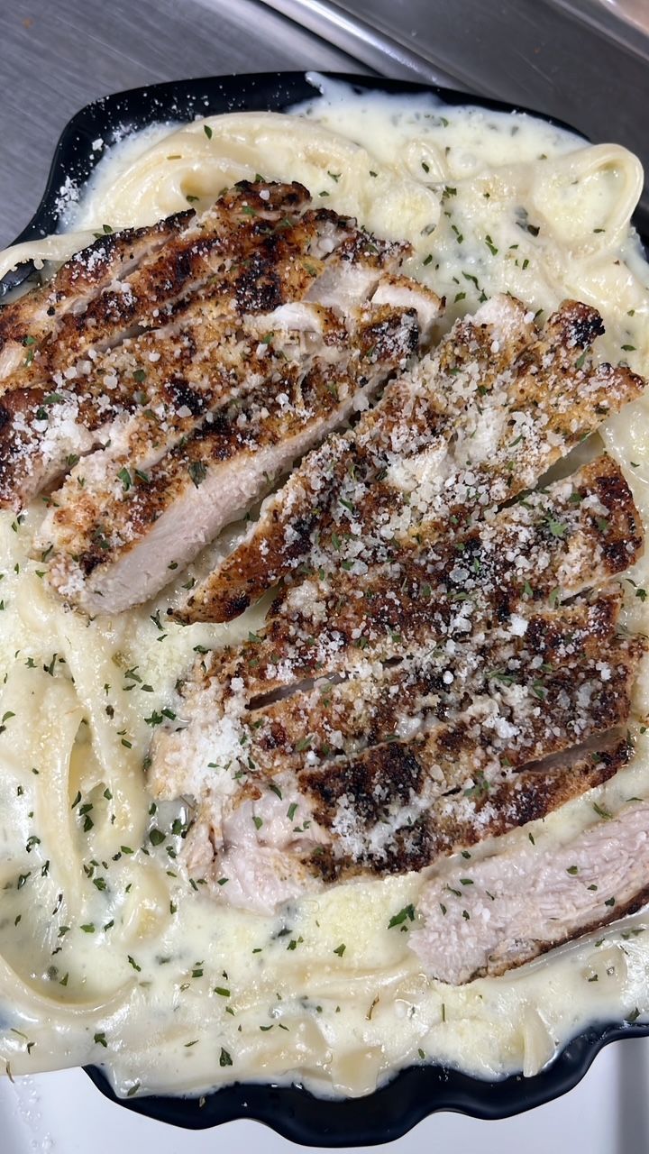 Pasta dish with sliced chicken in creamy sauce, sprinkled with herbs and grated cheese. At High Tide Harry's