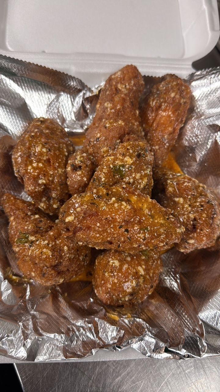 Close-up of fried chicken wings coated in seasoned breading, served in a foil-lined container. At High Tide Harry's