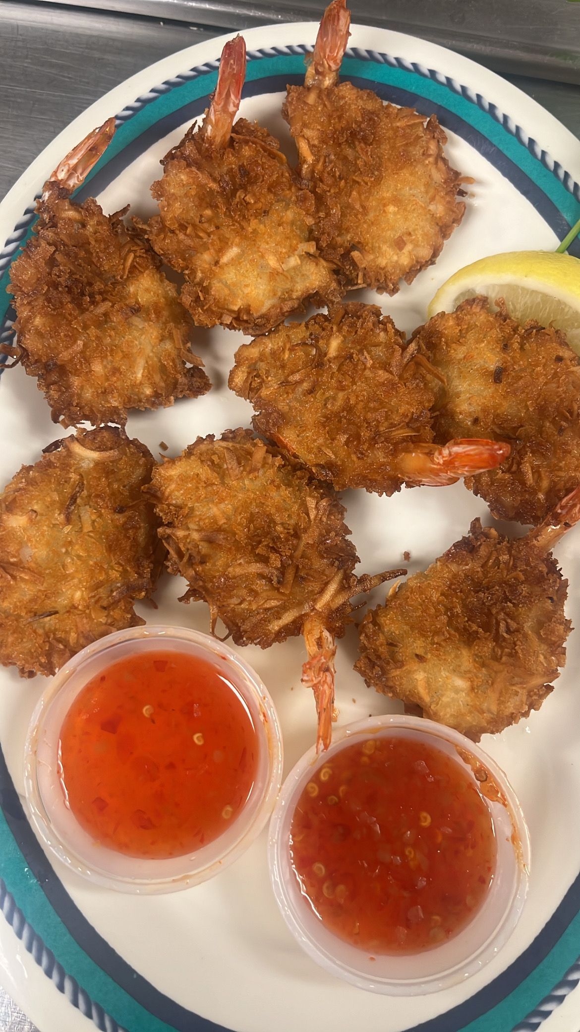 Coconut shrimp with dipping sauce and lemon on a plate. At High Tide Harry's