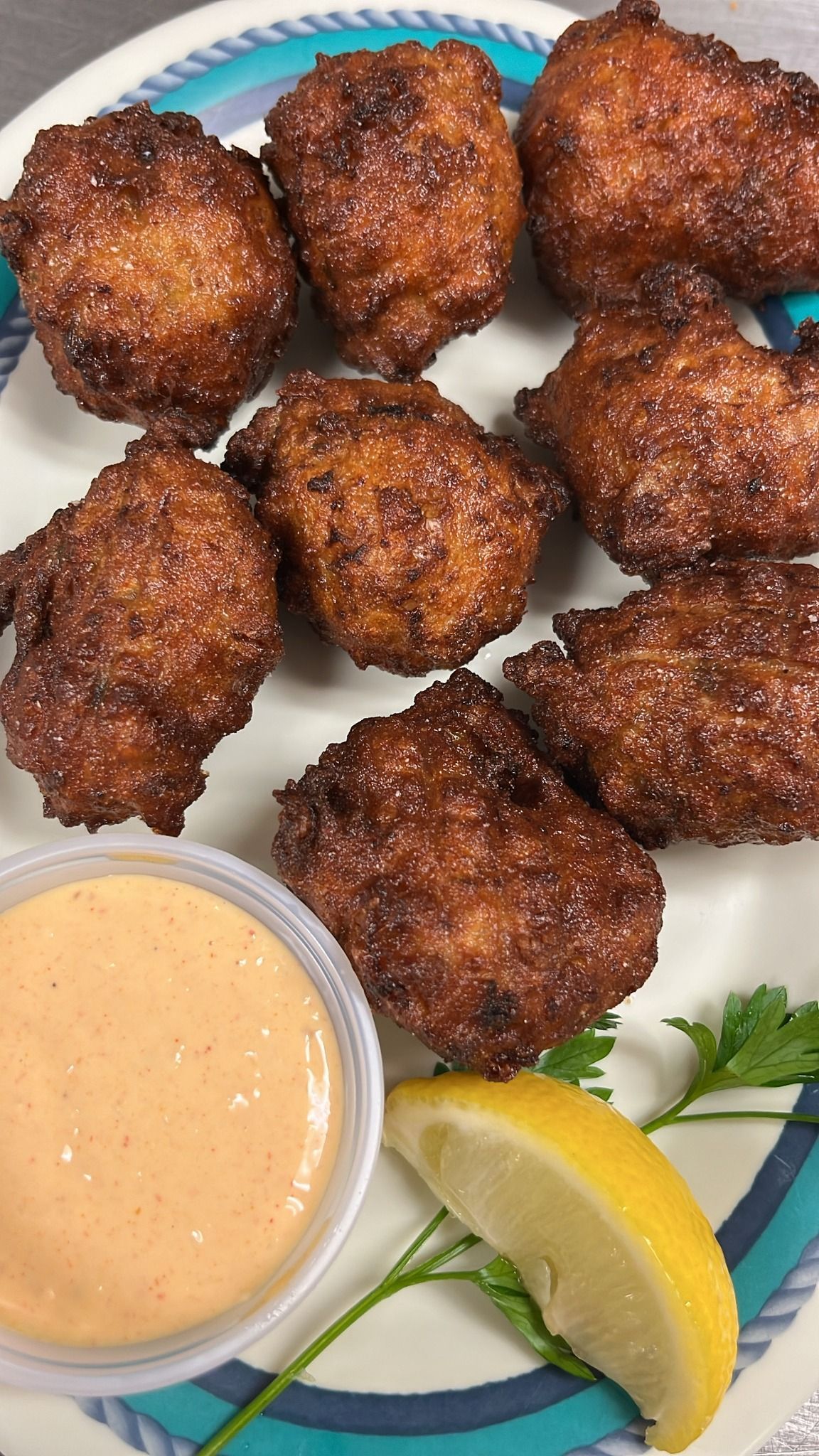 Plate of fried hushpuppies with dipping sauce and lemon slice. At High Tide Harry's