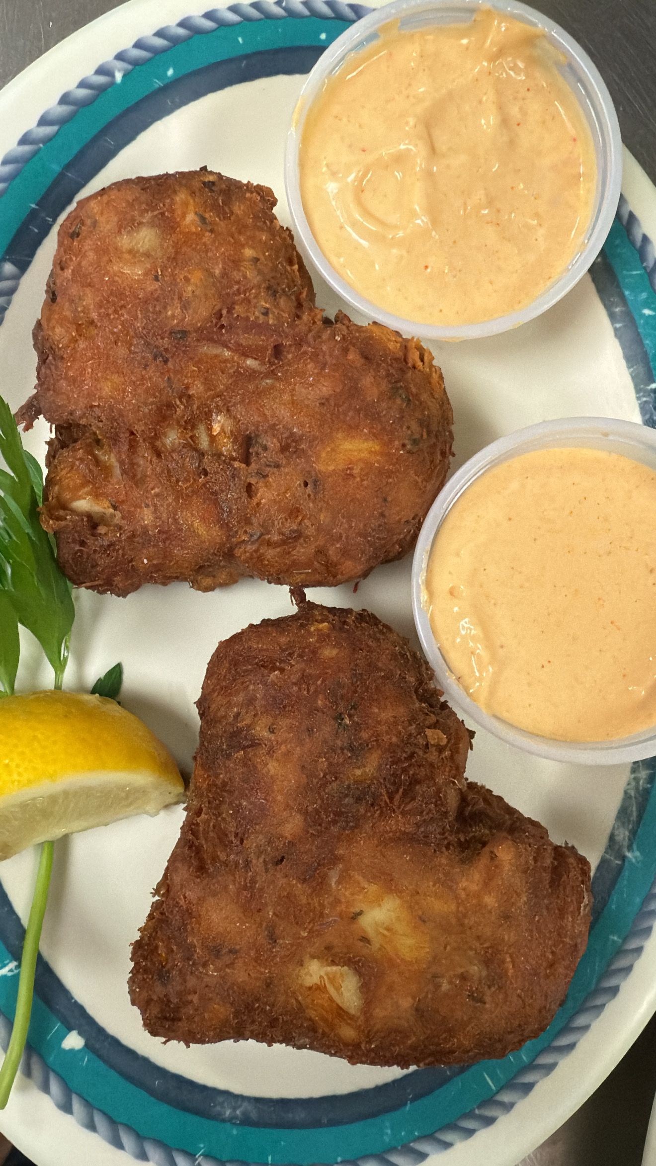 Two heart-shaped fried patties with two cups of pink sauce, lemon wedge, and parsley on a plate. At High Tide Harry's