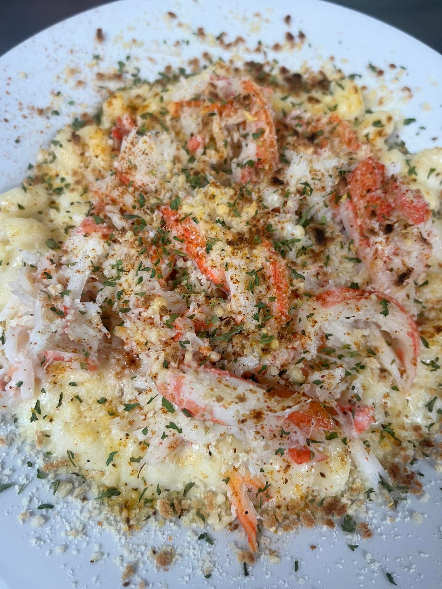 Pasta dish with crab meat, cheese, and herbs, on a white plate. At High Tide Harry's