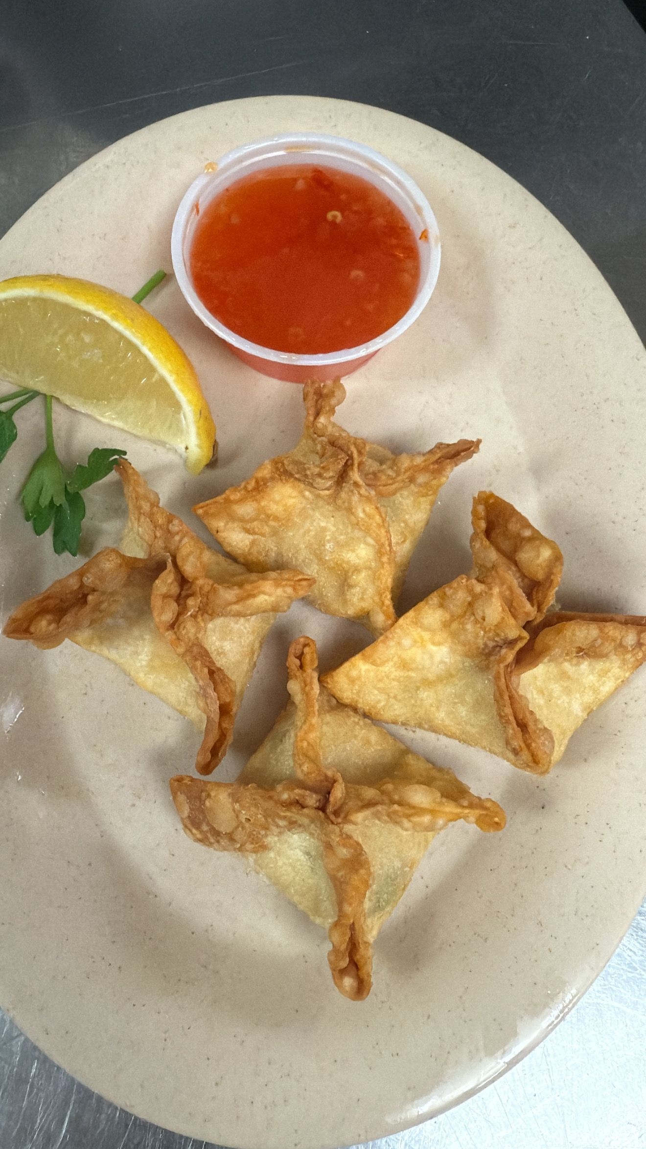 Crispy wontons on a plate with dipping sauce and lemon slice. At High Tide Harry's