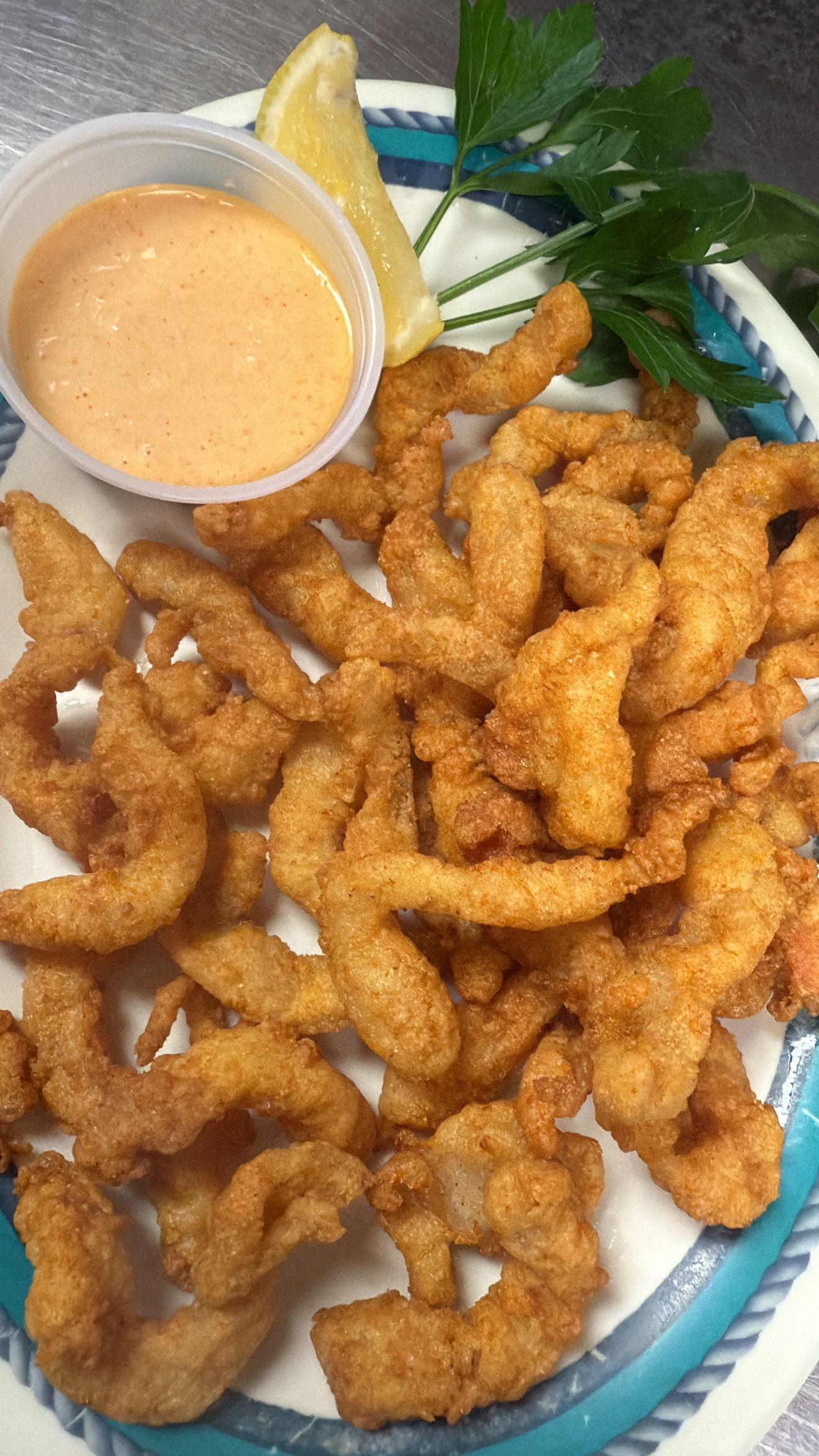 Fried shrimp with dipping sauce and lemon slice on a plate. At High Tide Harry's