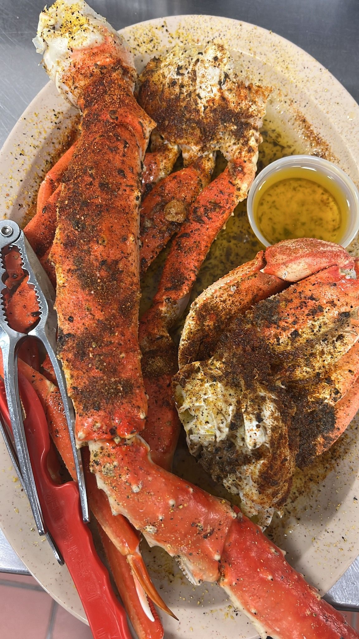 Plate of cooked king crab legs with seasoning, butter, and a cracker. At High Tide Harry's