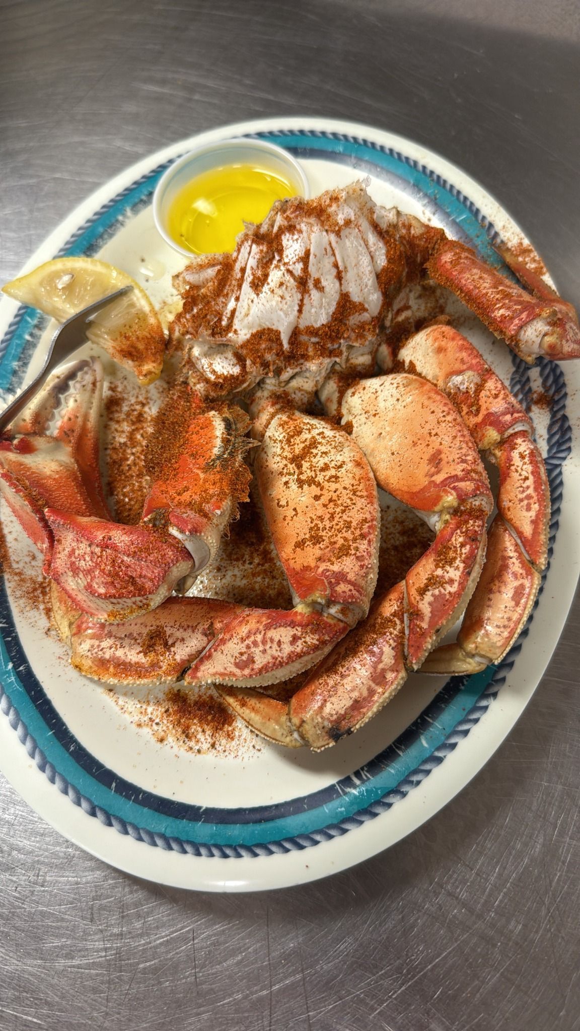 Crab legs seasoned with spices on a plate with butter and a lemon wedge. At High Tide Harry's
