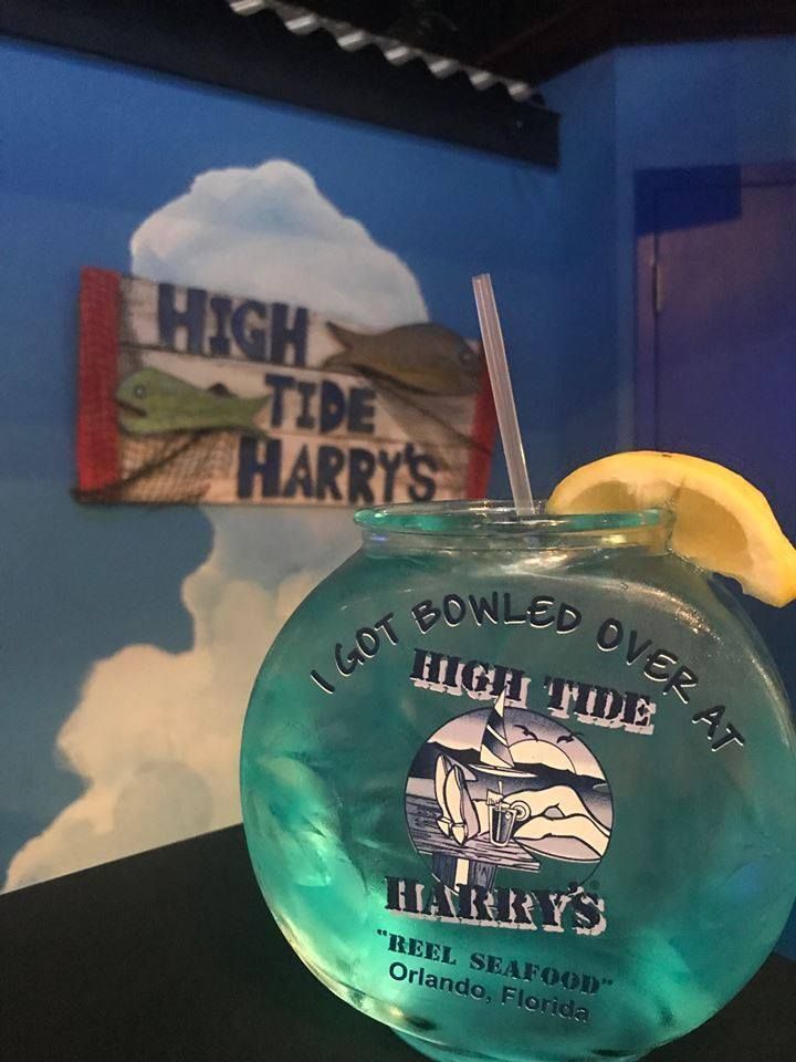 Cocktail in a fishbowl at High Tide Harry's in Orlando. Blue drink with lemon, against a blue wall with a sign.