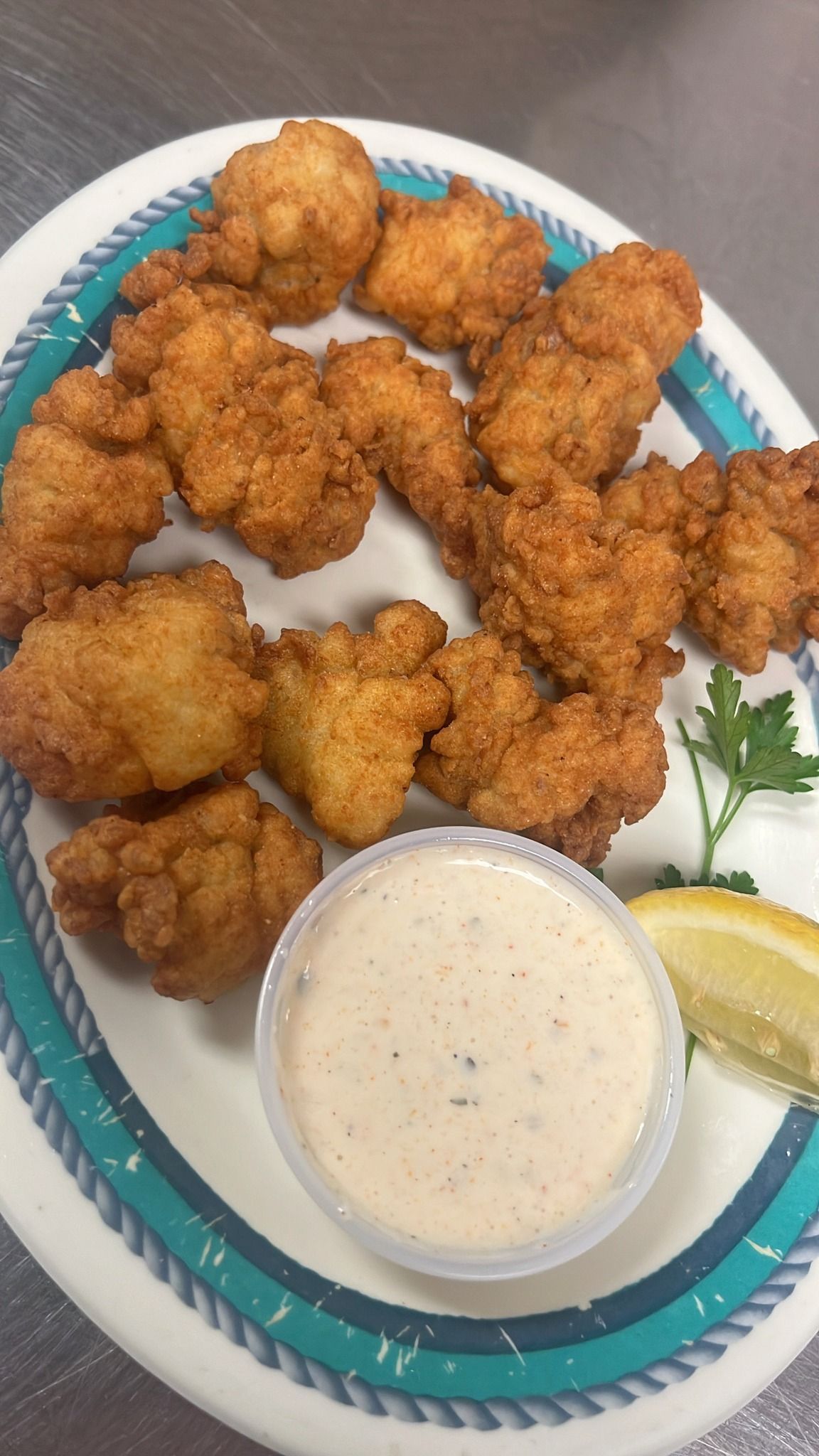 Plate of fried food with a dipping sauce and lemon slice. At High Tide Harry's