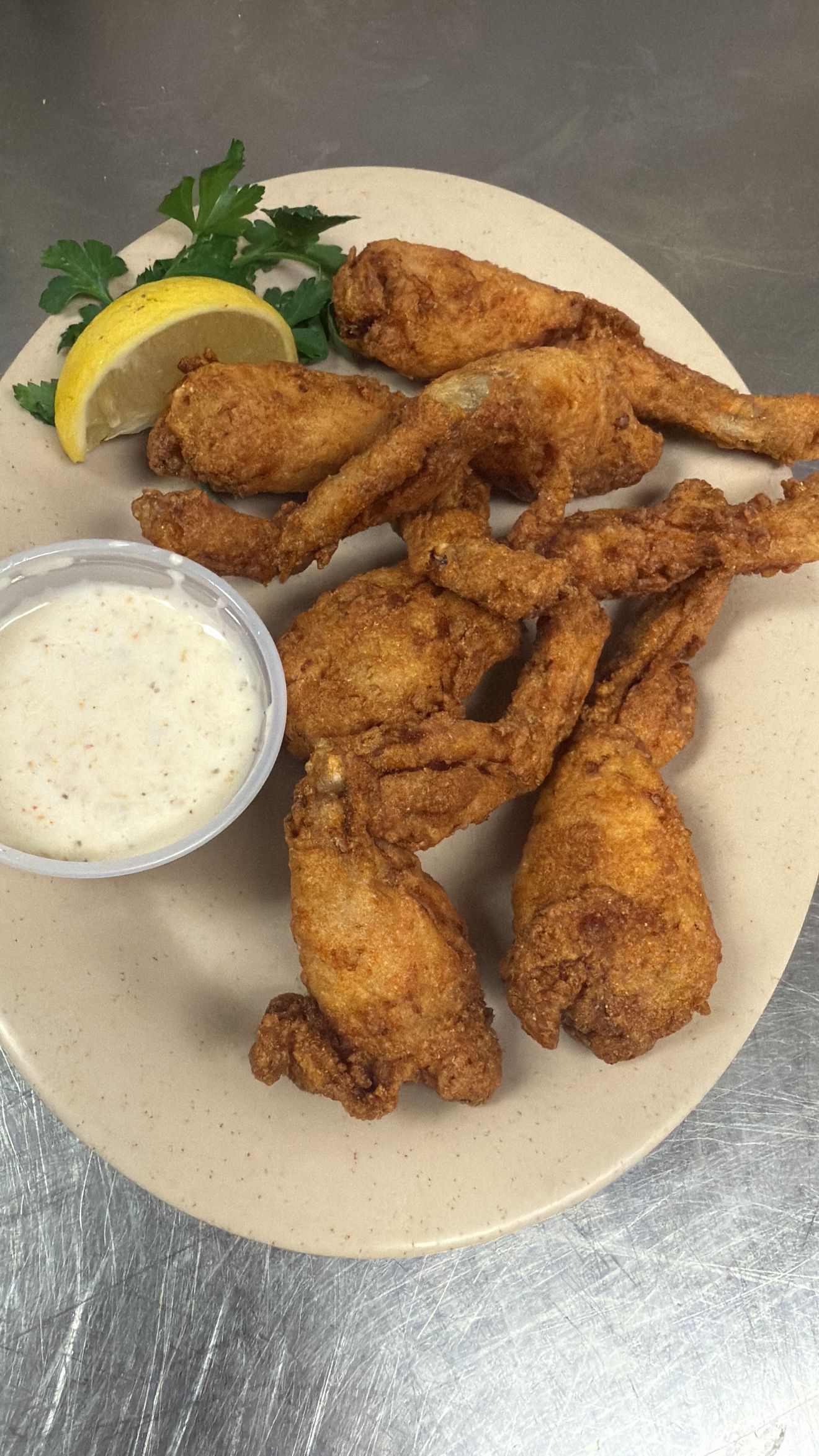 Fried frog legs on a plate with dipping sauce and lemon. At High Tide Harry's