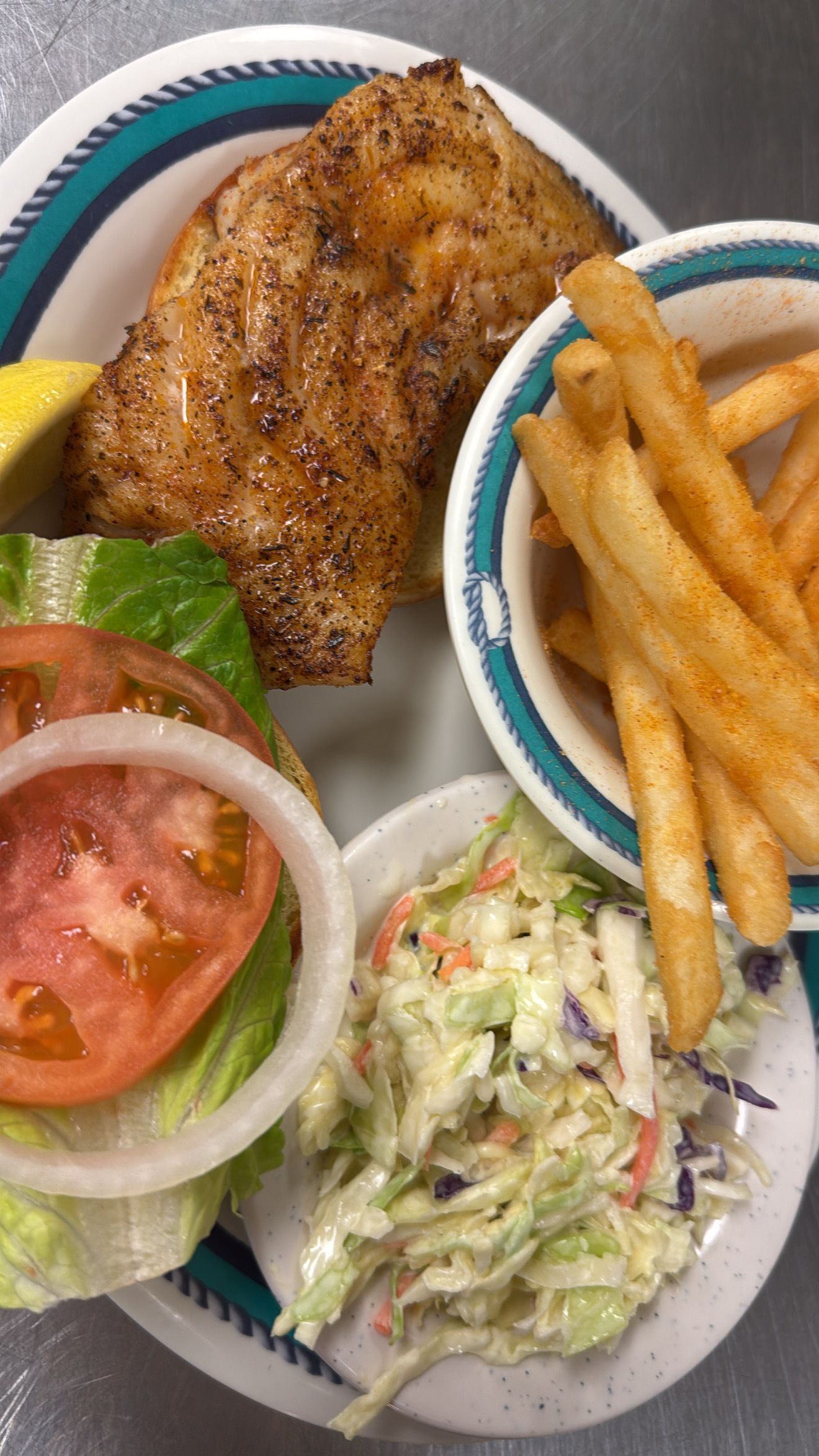 Plate with blackened fish, fries, coleslaw, tomato, onion, and lettuce. At High Tide Harry's