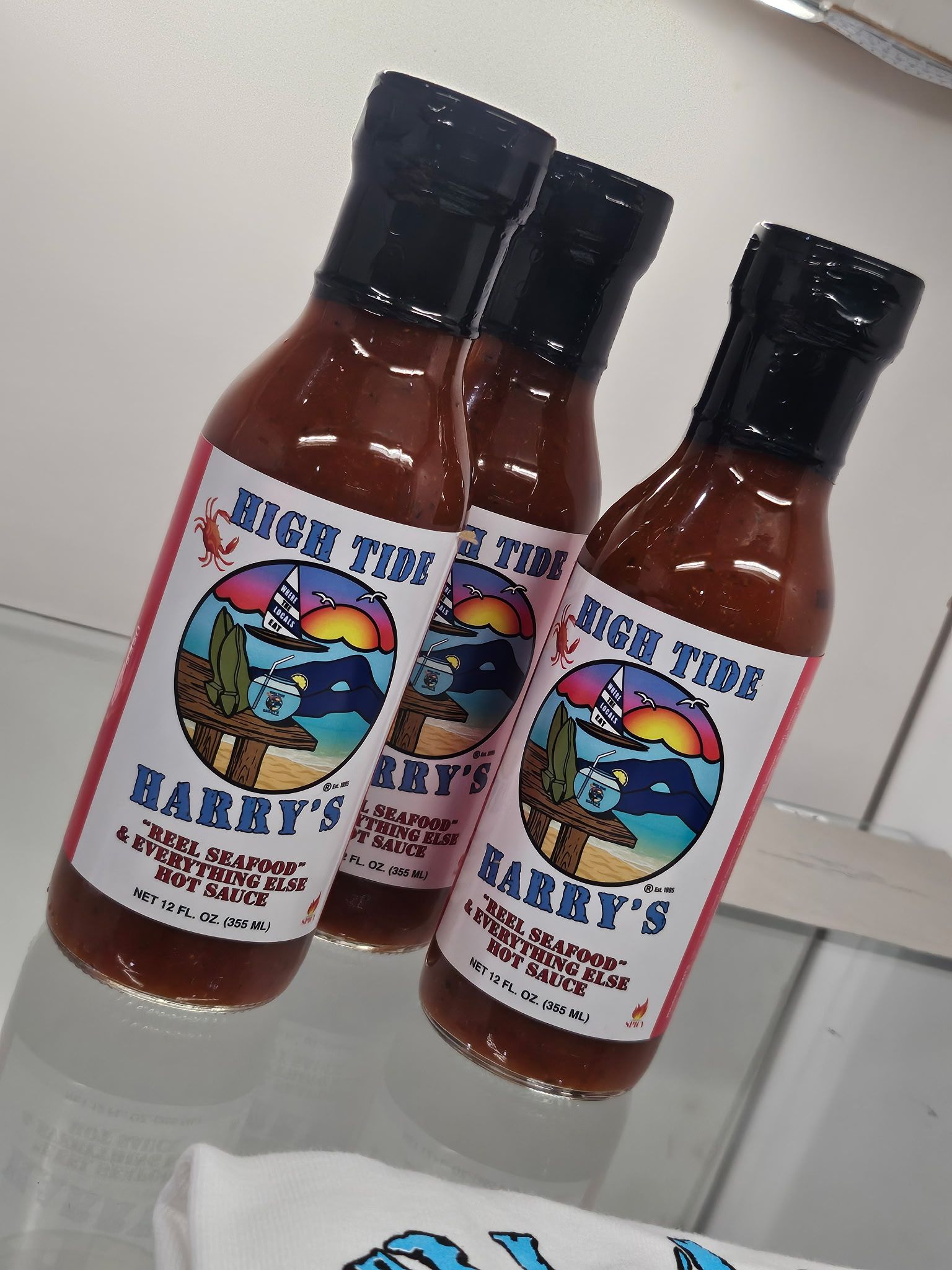 Three bottles of Harry's hot sauce with a southwestern-themed label, featuring a desert landscape. At High Tide Harry's