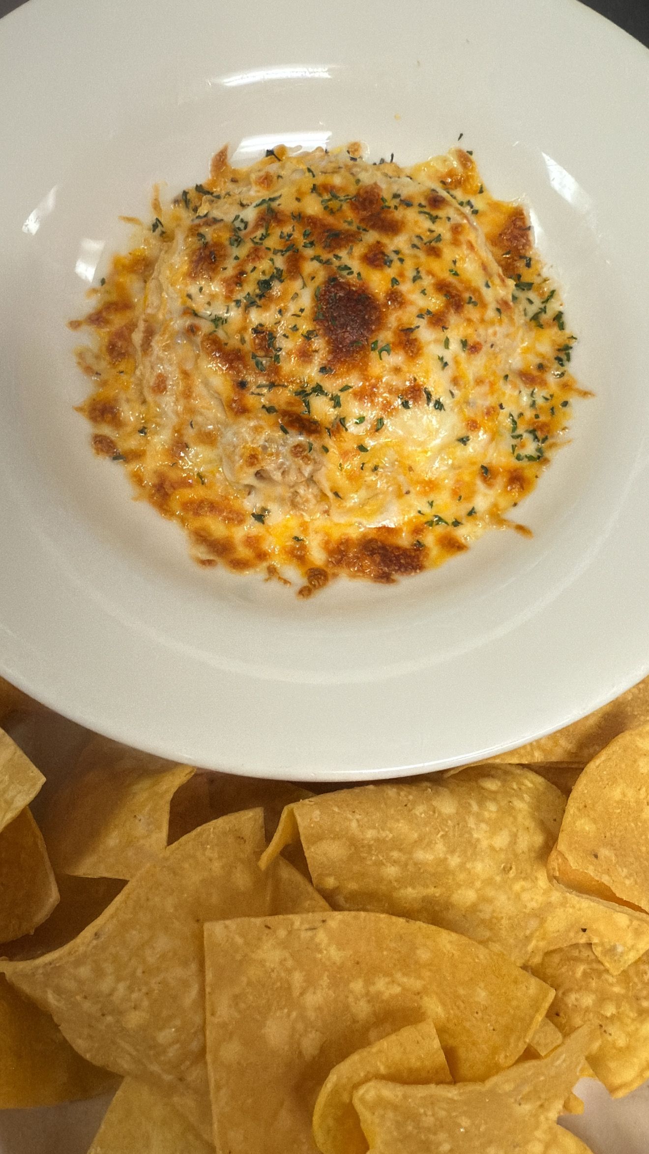 Cheesy dip in a white bowl, served with tortilla chips.