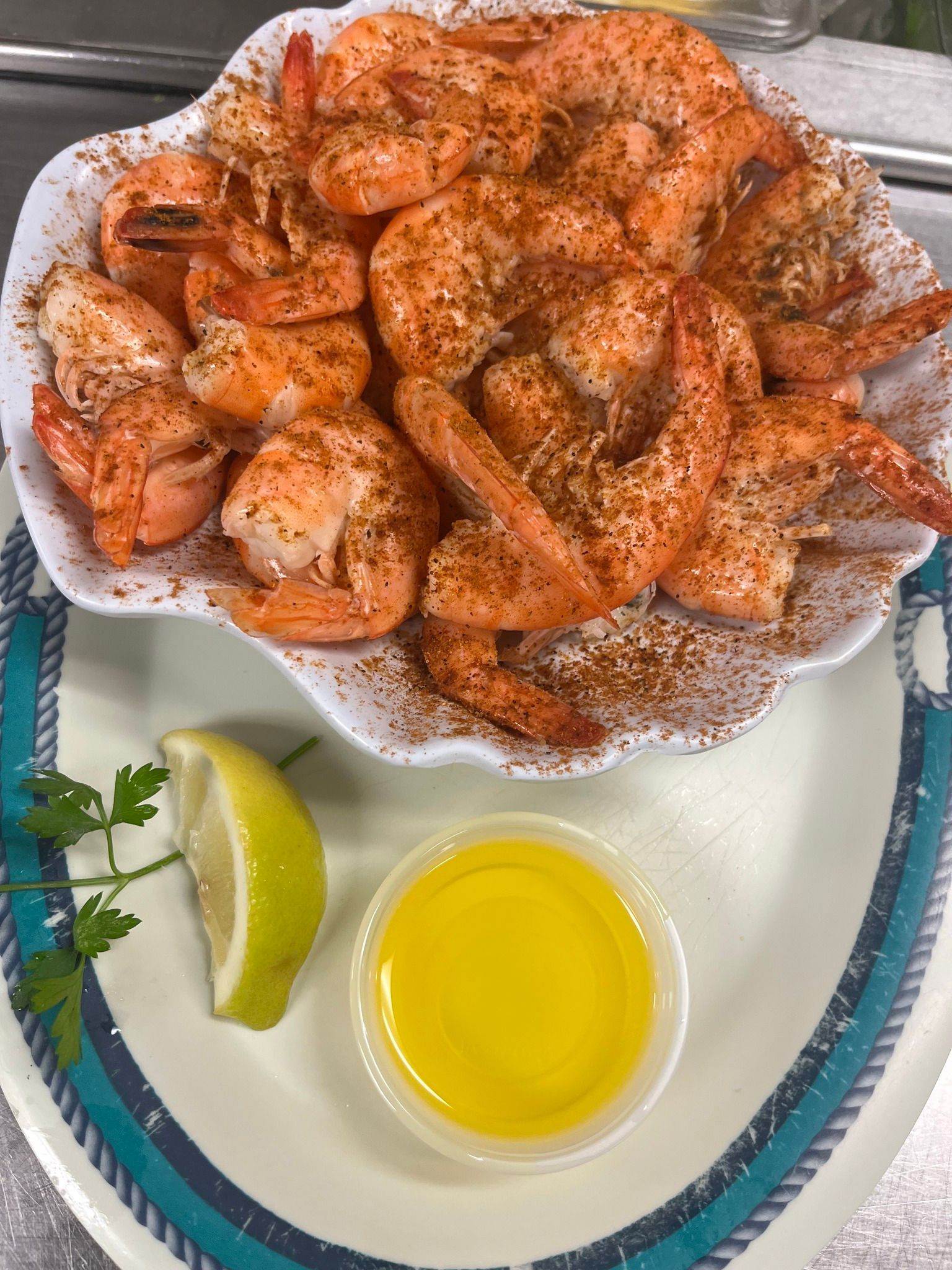 Shrimp dish with seasoning in white bowl, lemon, parsley, and butter. At High Tide Harry's