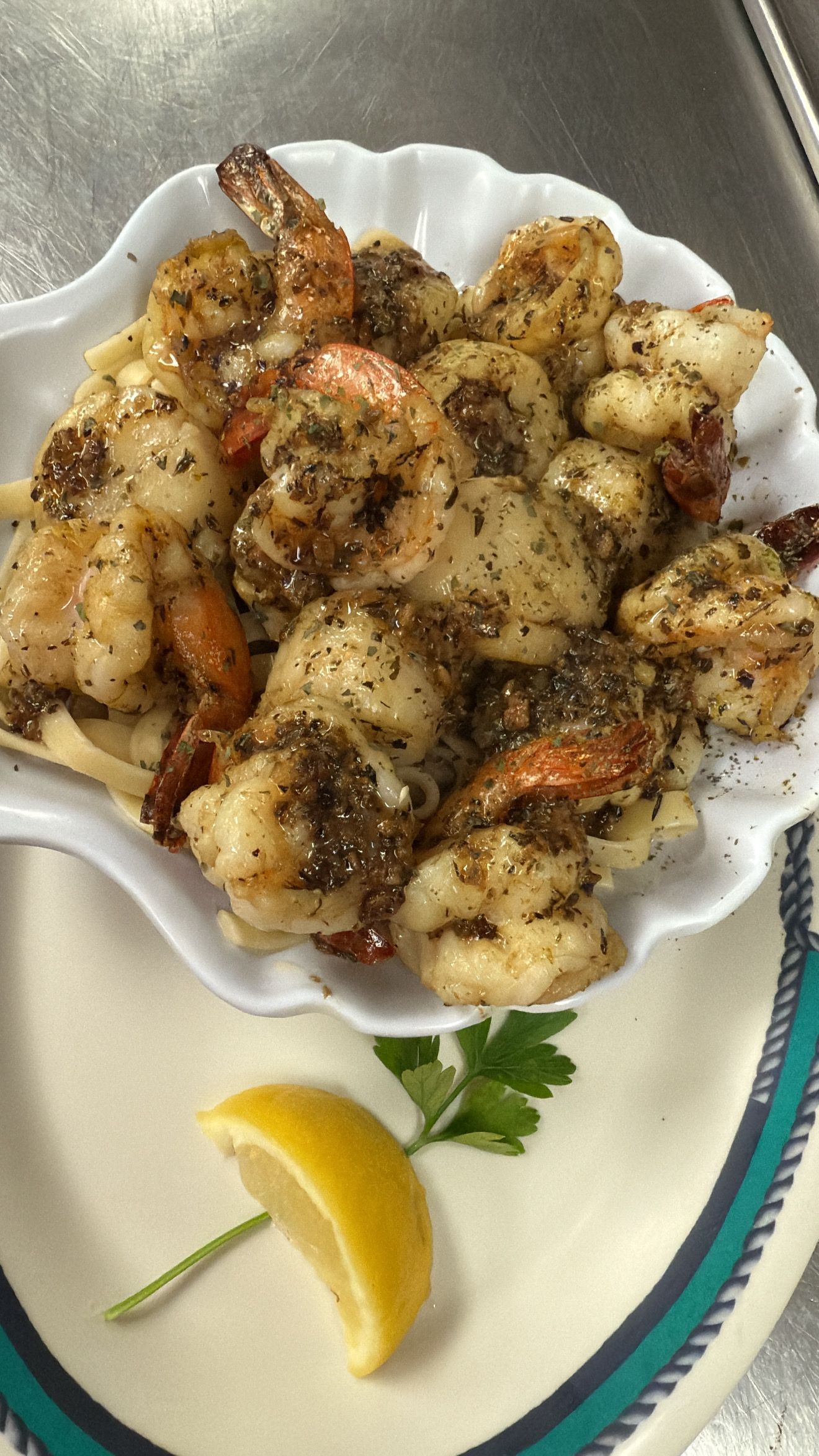 A shell-shaped dish with seasoned shrimp, a lemon slice, and parsley. At High Tide Harry's