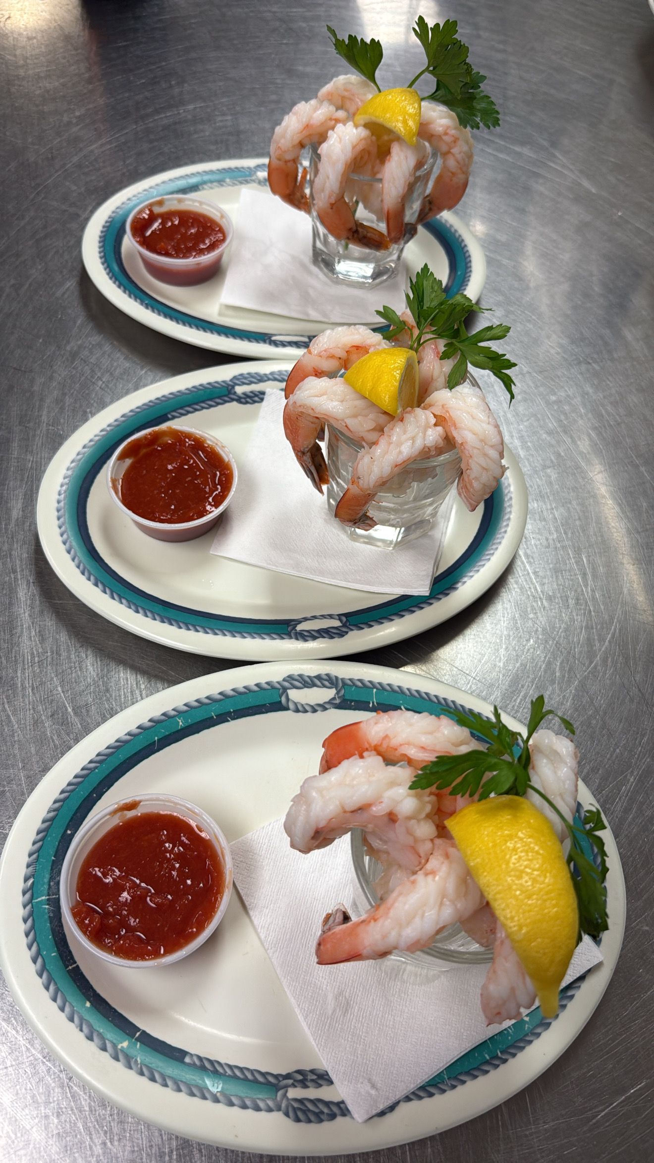 Three shrimp cocktail servings on plates, with sauce and lemon garnish. At High Tide Harry's