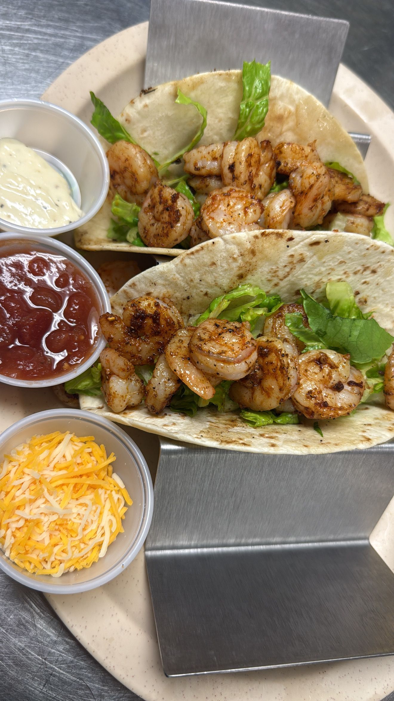 Shrimp tacos with salsa, cheese, and sauce on a plate. At High Tide Harry's