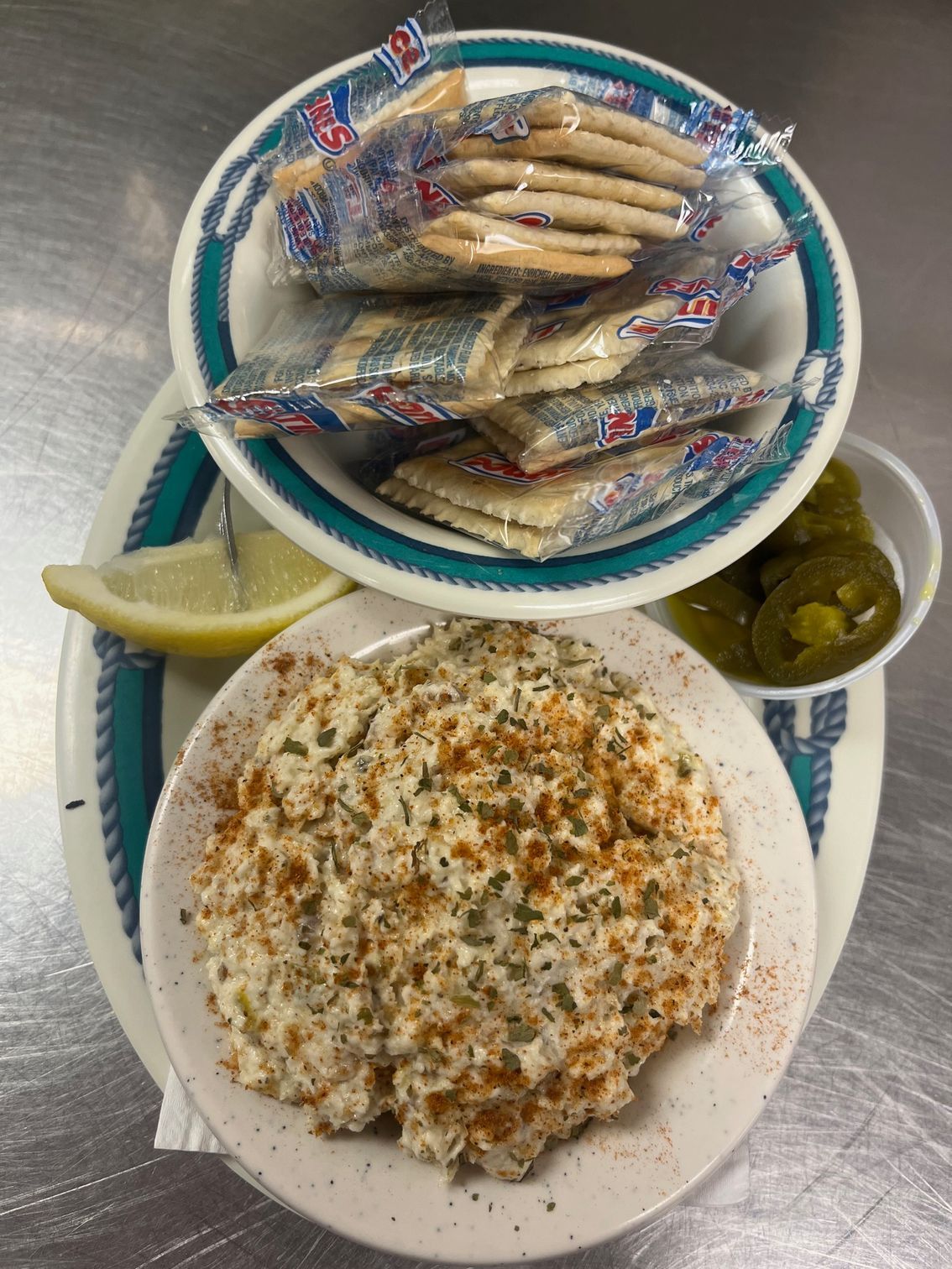 Plate of seafood salad with crackers, lemon, and jalapeños.