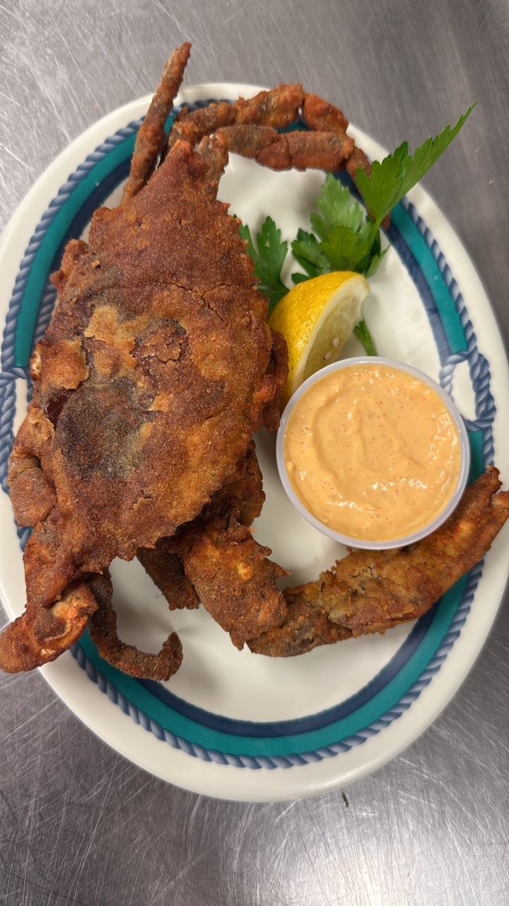 Fried soft-shell crab on a plate with sauce, lemon, and parsley. At High Tide Harry's